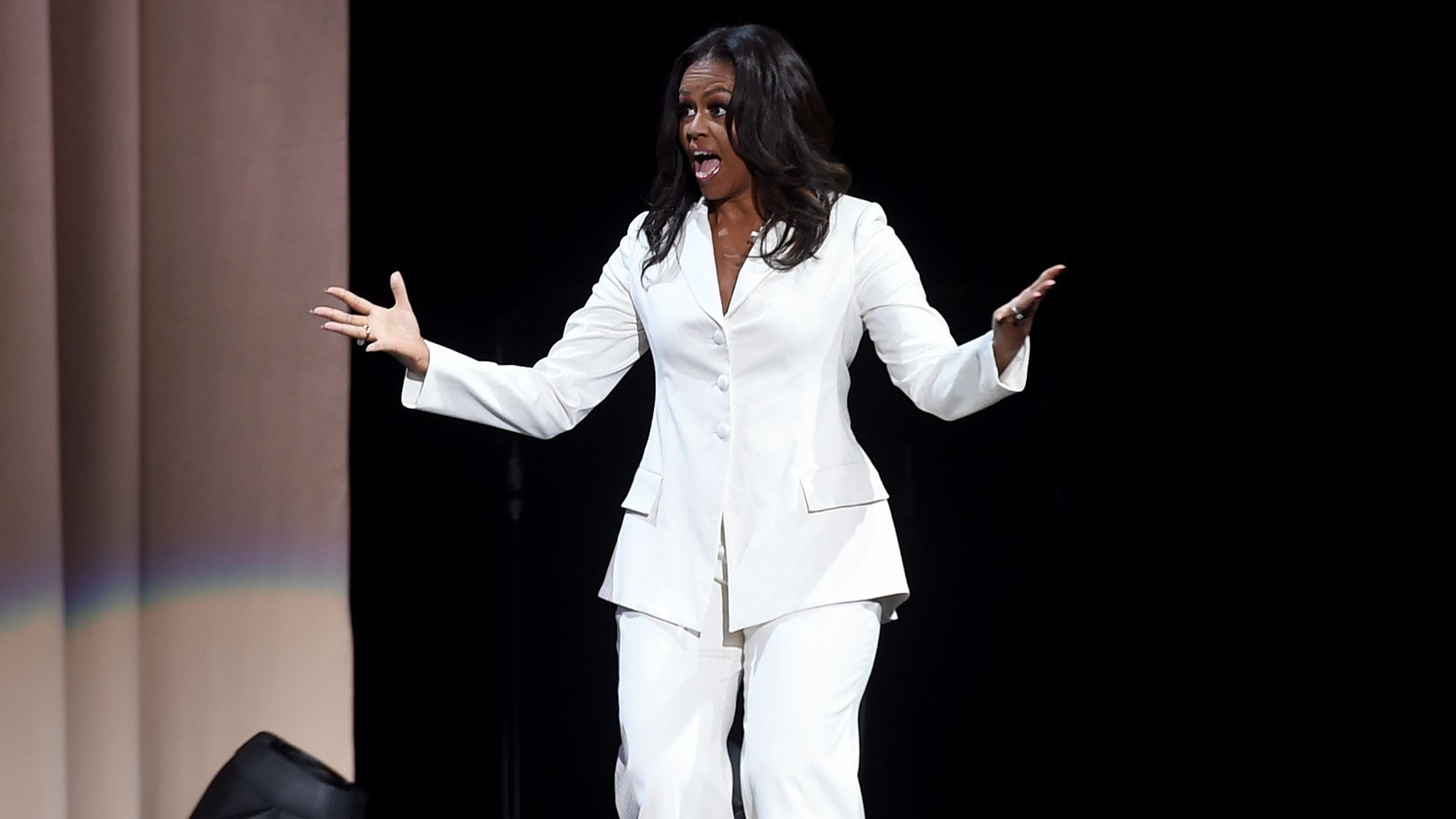 Michelle Obama gestures enthusiastically on stage