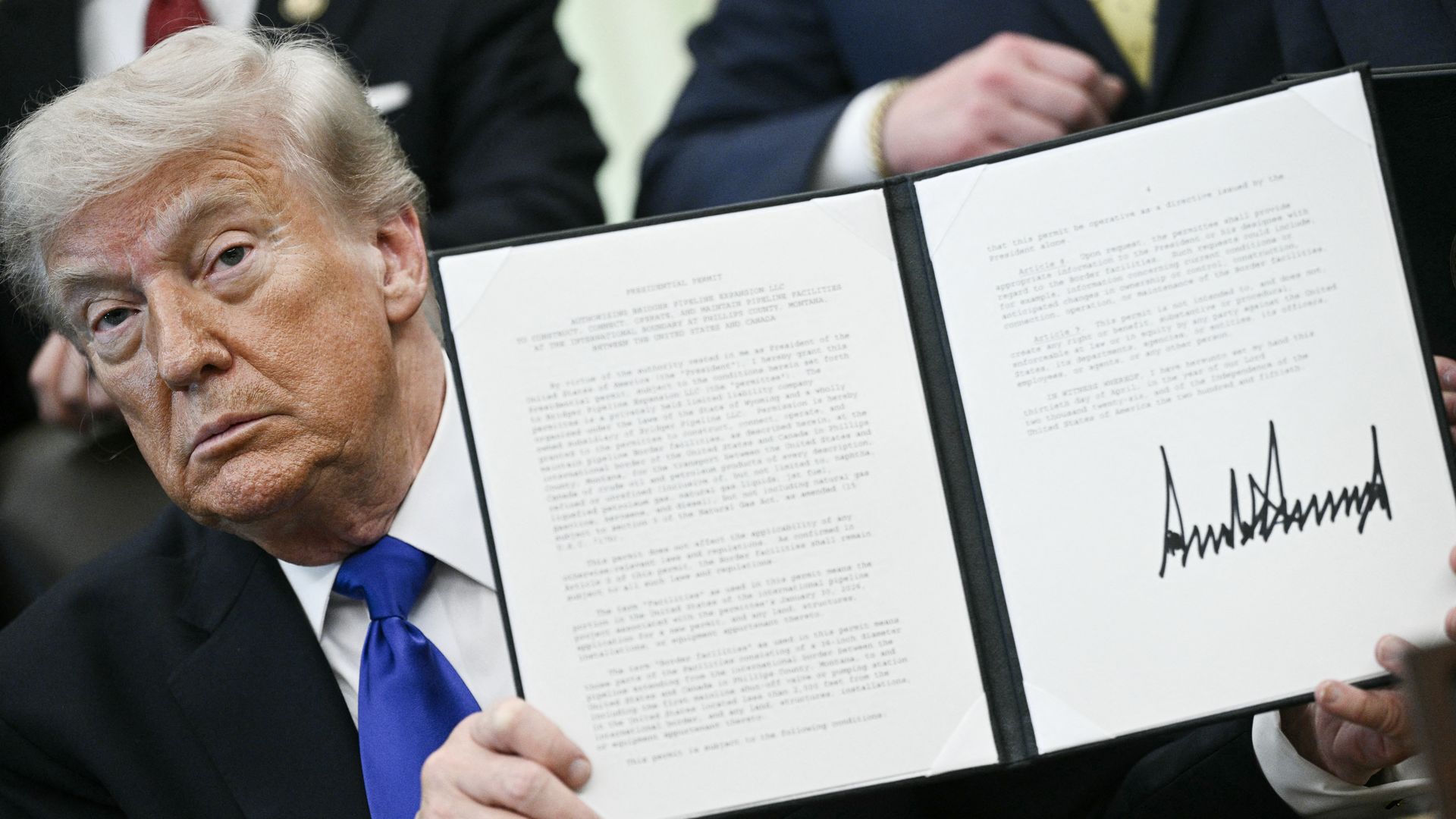 US President Donald Trump holds a signed executive order in the Oval Office at the White House 