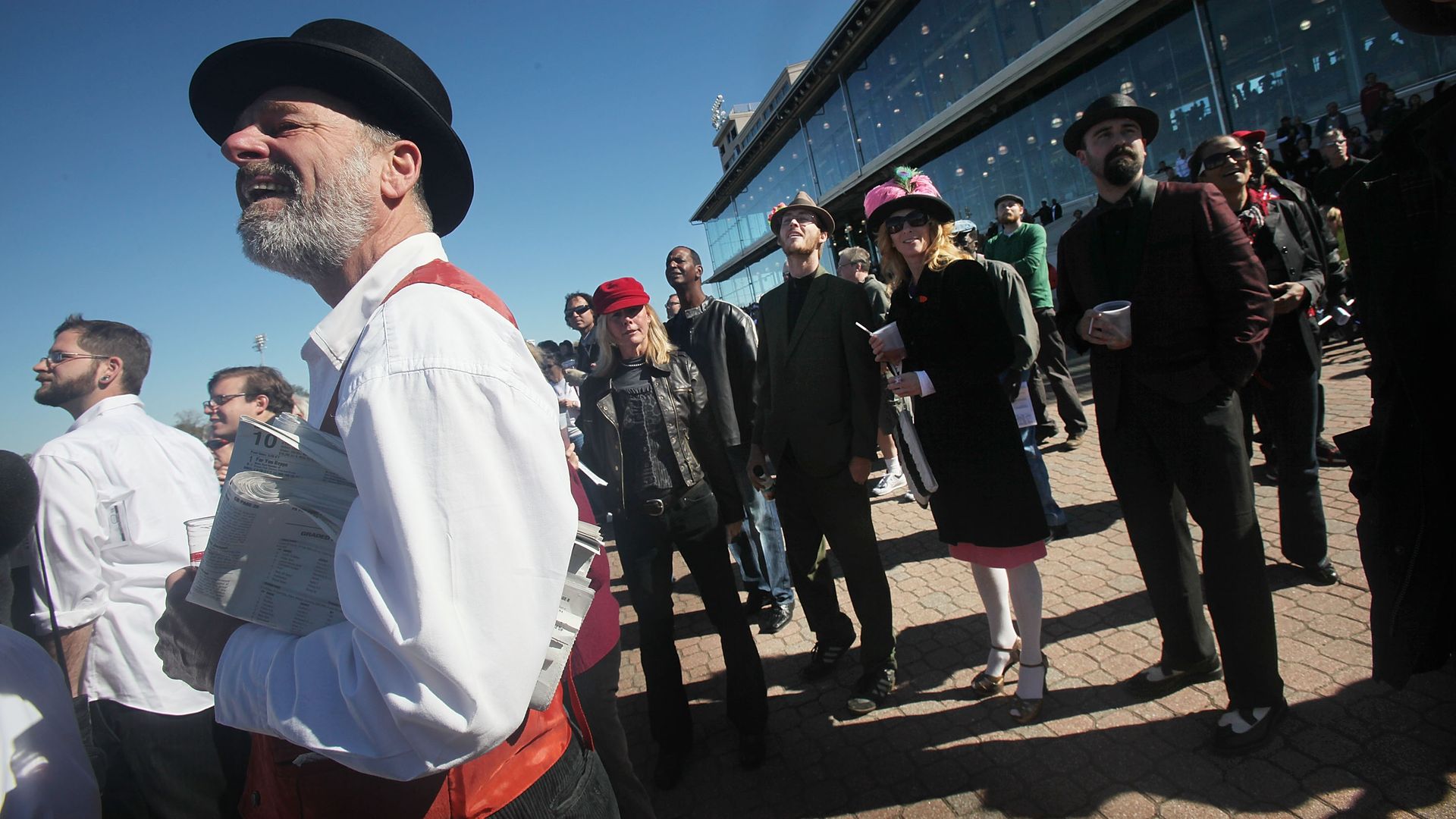 A crowd watches a horse race, off-camera, wearing vintage holiday attire.