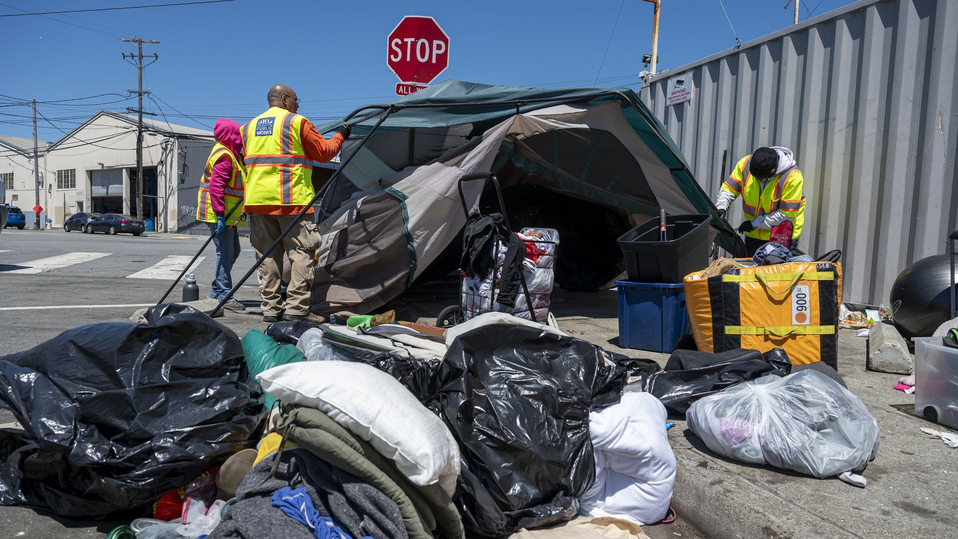 Photo of three city workers clearing a homeless encampment sweep