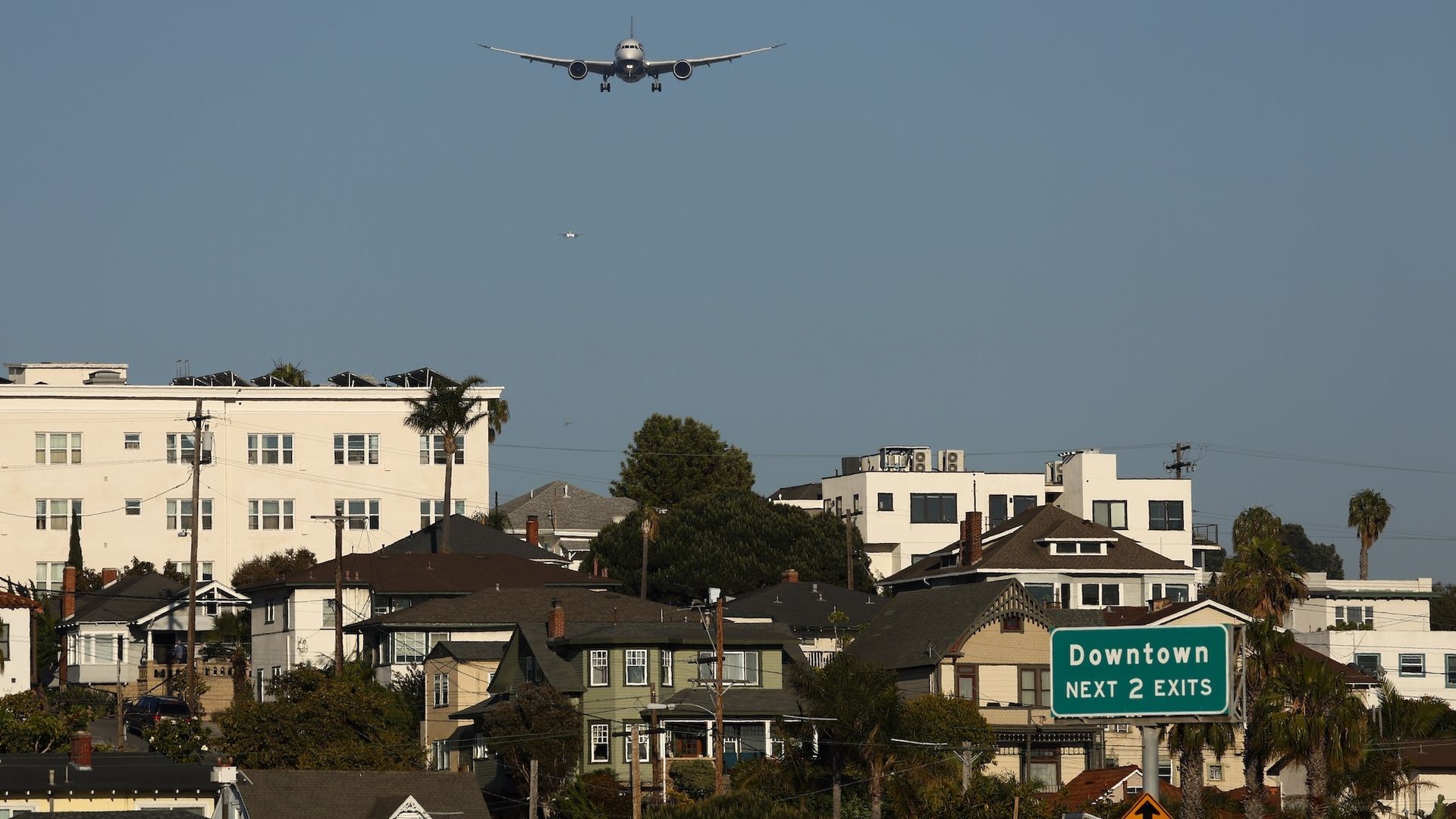 An airplane flies over homes and buildings in downtown San Diego. 