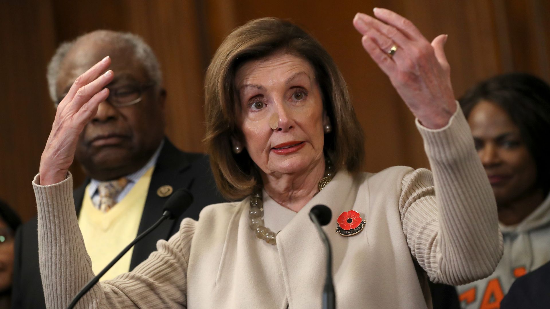 In this image, Pelosi stands with her arms above her head.