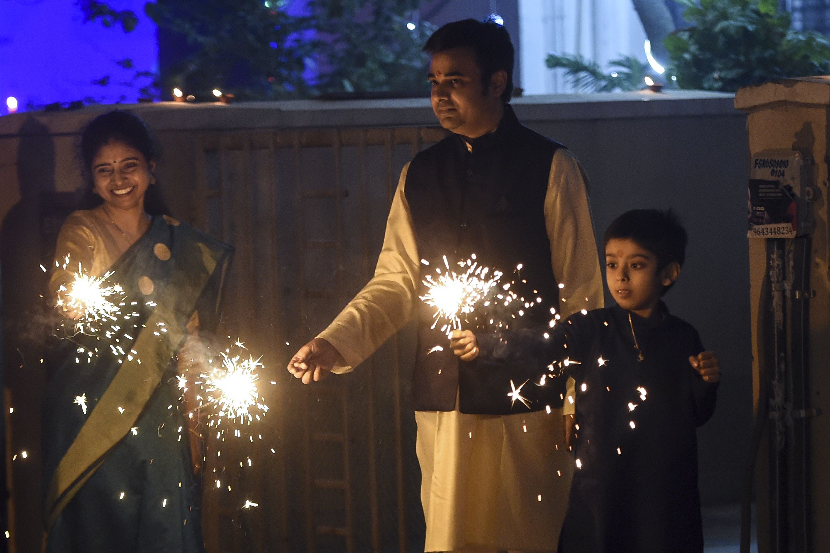 A family lights a sparkler during Diwali, the Hindu Festival of Lights, in Faridabad on November 14, 2020. (Photo by Money SHARMA / AFP) (Photo by MONEY SHARMA/AFP via Getty Images)