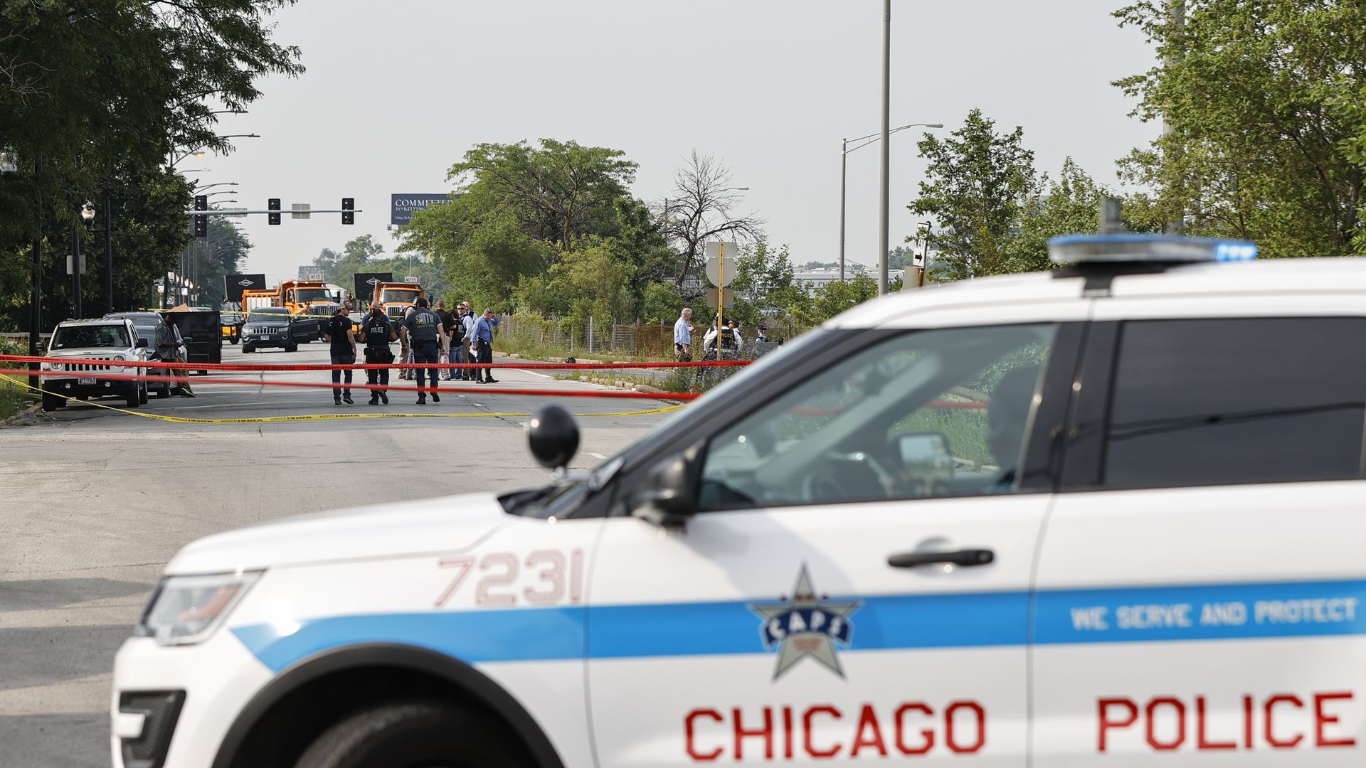 Photo of a Chicago police car parked next to a crime scene that's taped off and has multiple officers standing around