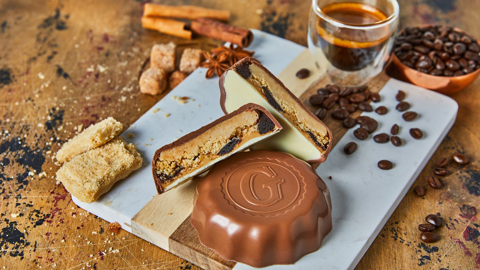 A Goo Goo candy bar on a cutting board next to coffee beans and espresso.