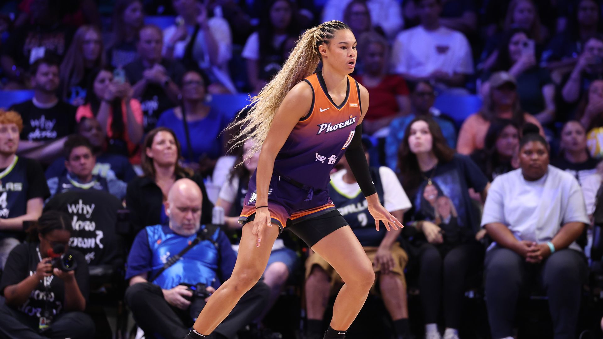 A basketball player on a court with a Phoenix Mercury jersey. 