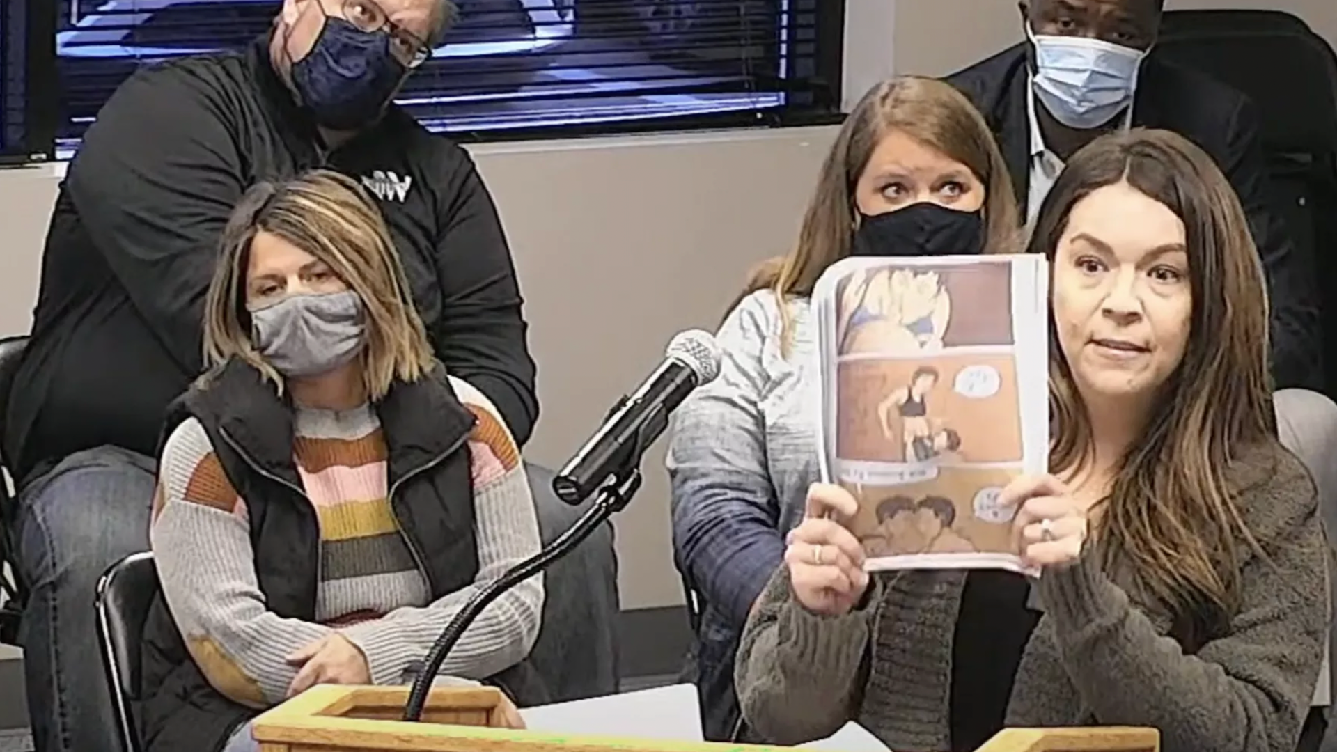 A photo of a person holding up copies of "Gender Queer"