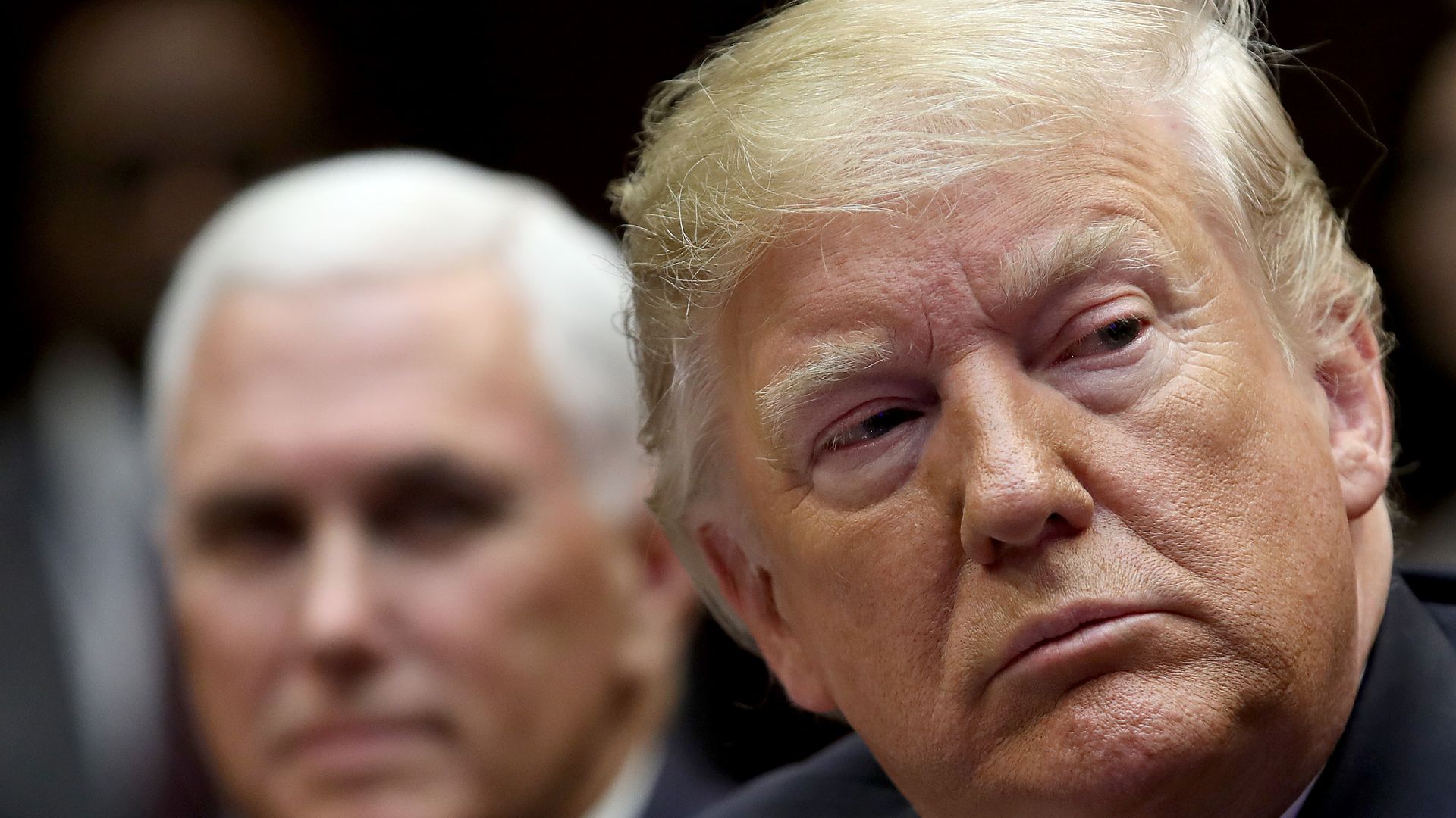 In this image, Trump looks to his right while Mike Pence sits behind him.