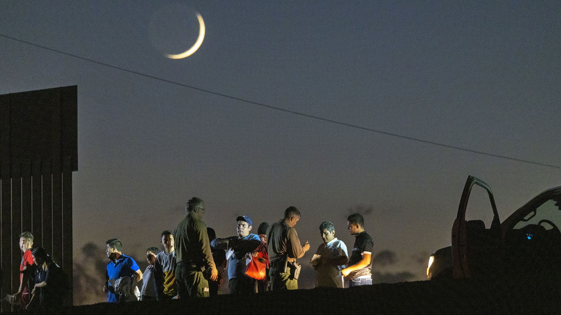 Border patrol agents take people into custody next to the U.S.-Mexico border fence