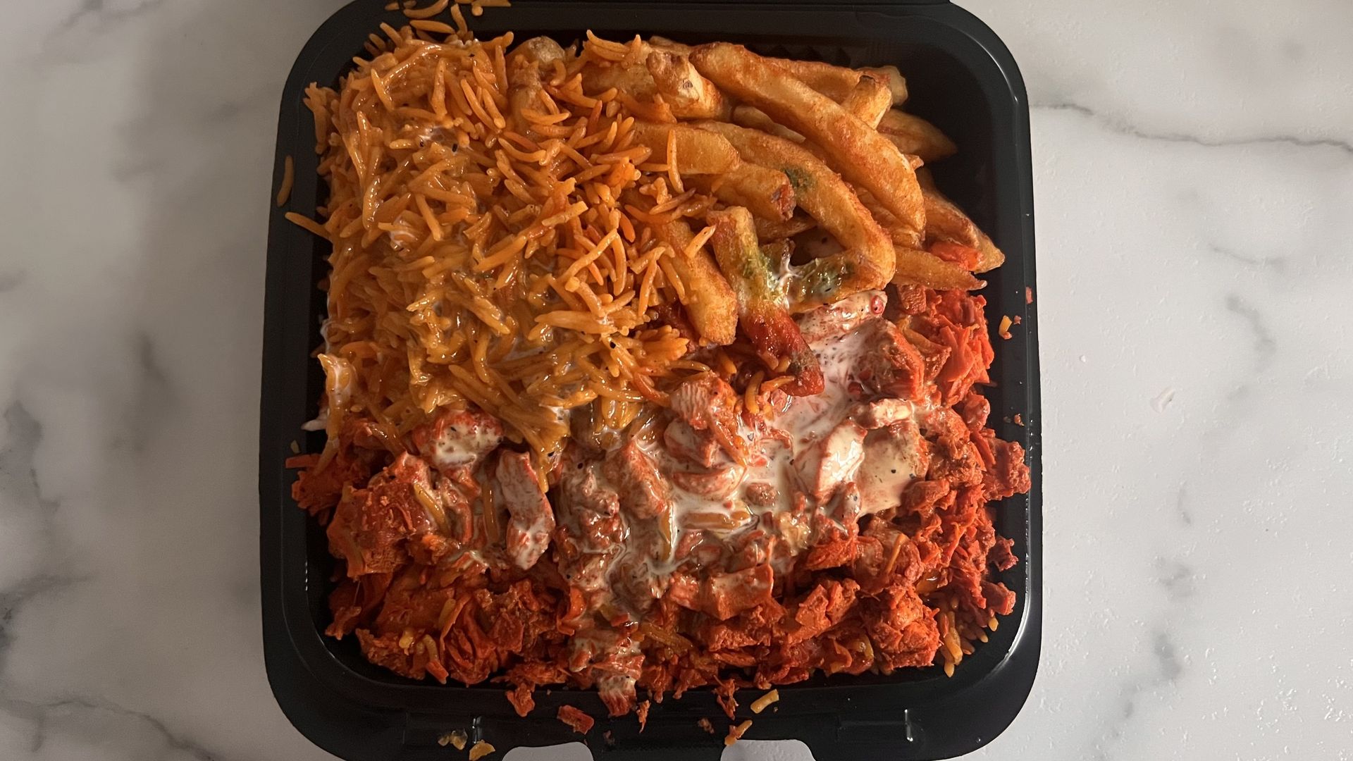 a giant plate of food including fries, rice, chicken and sauces