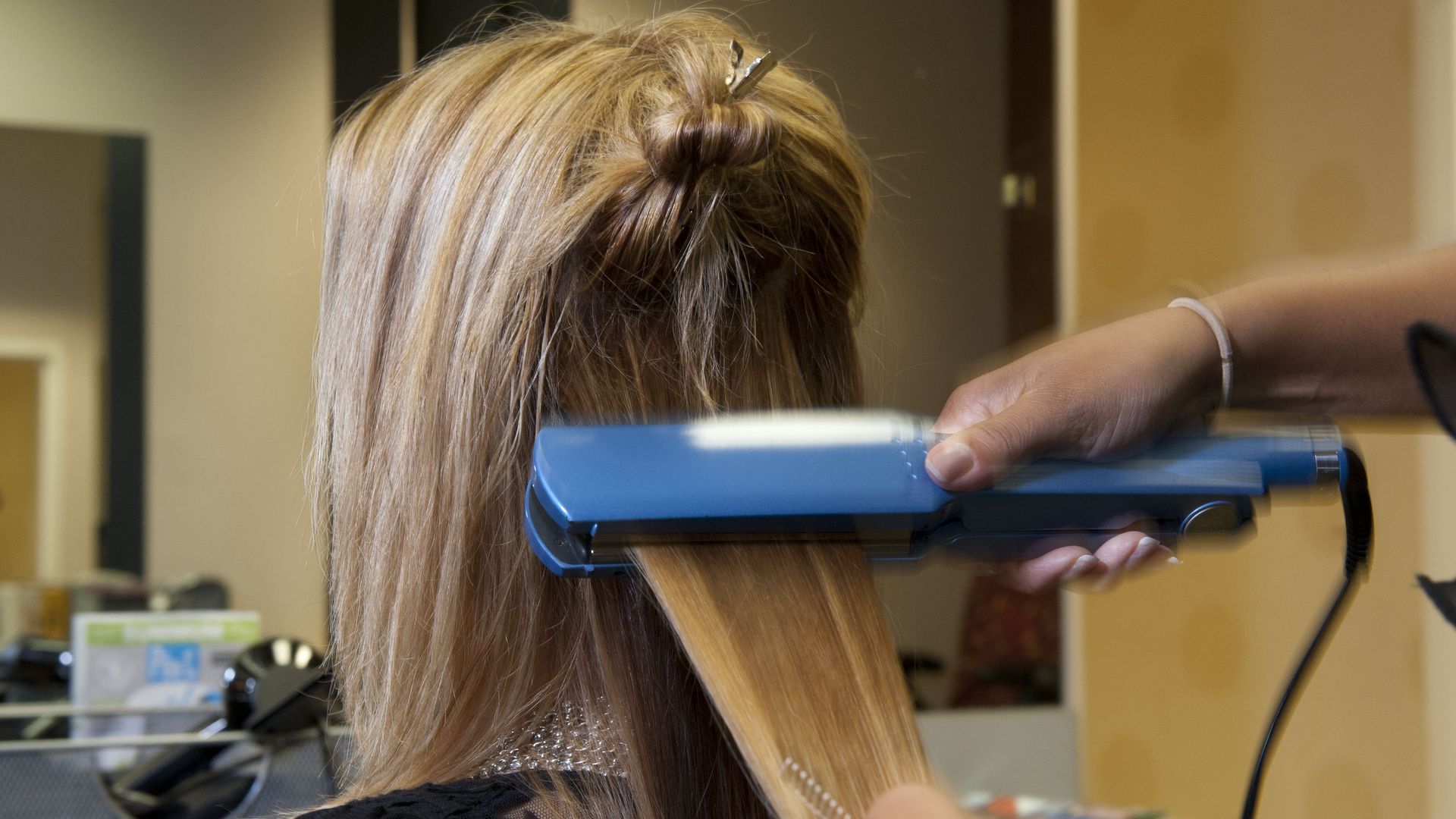 A woman gets her hair straightened at a salon.