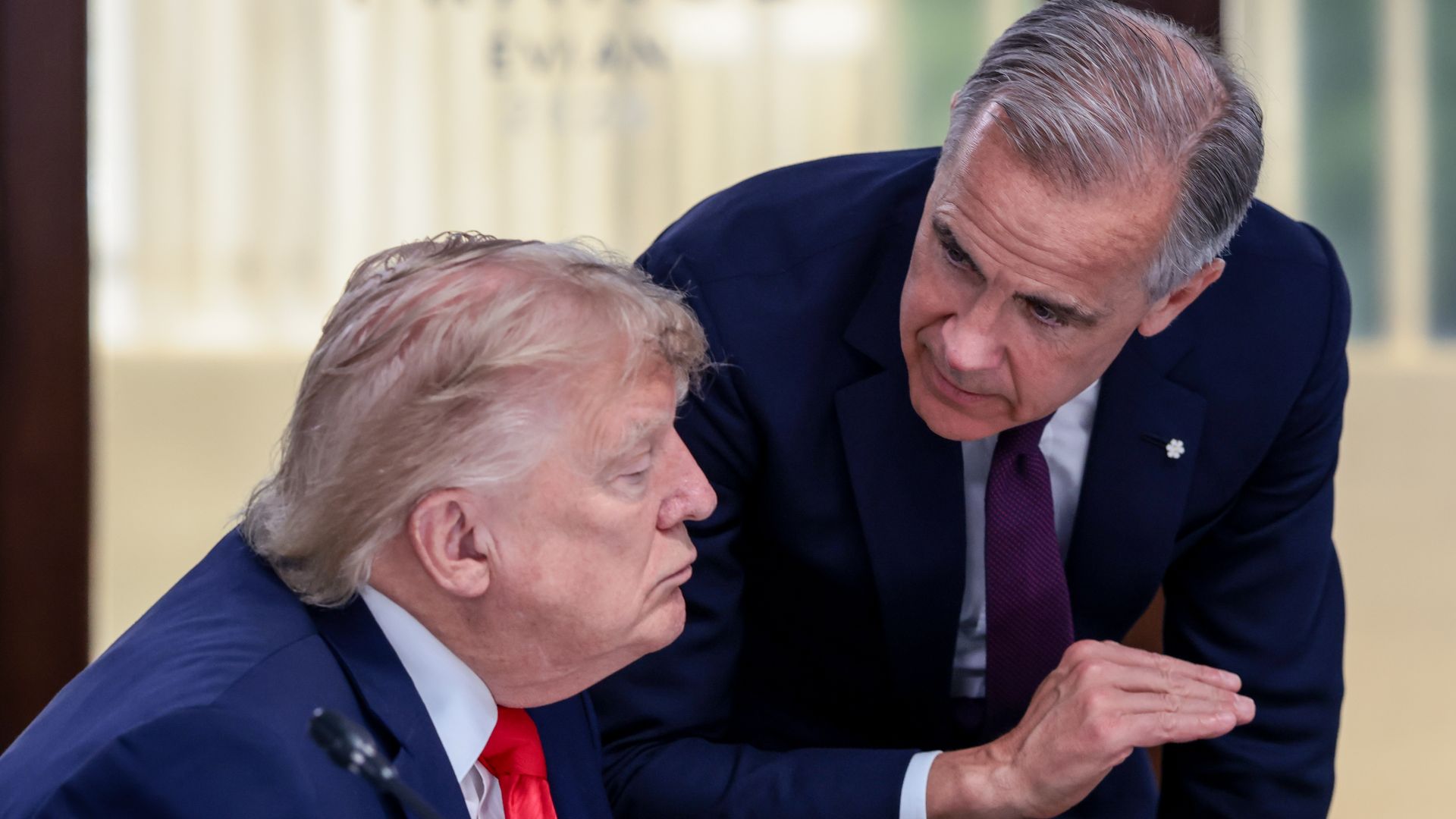 Donald Trump, sitting, and Mark Carney, standing.