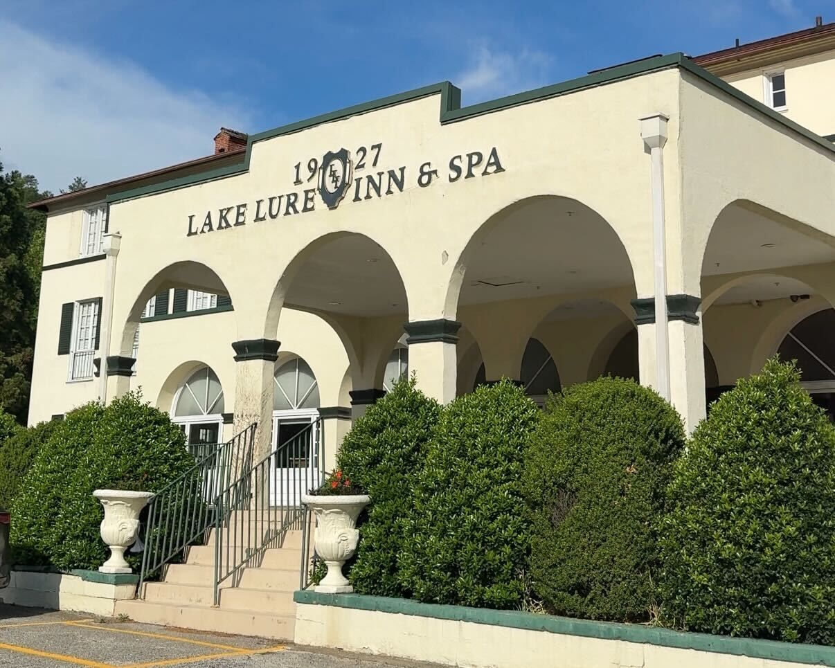 Exterior view of Lake Lure Inn & Spa with arched entryways, stairs and landscaped greenery.