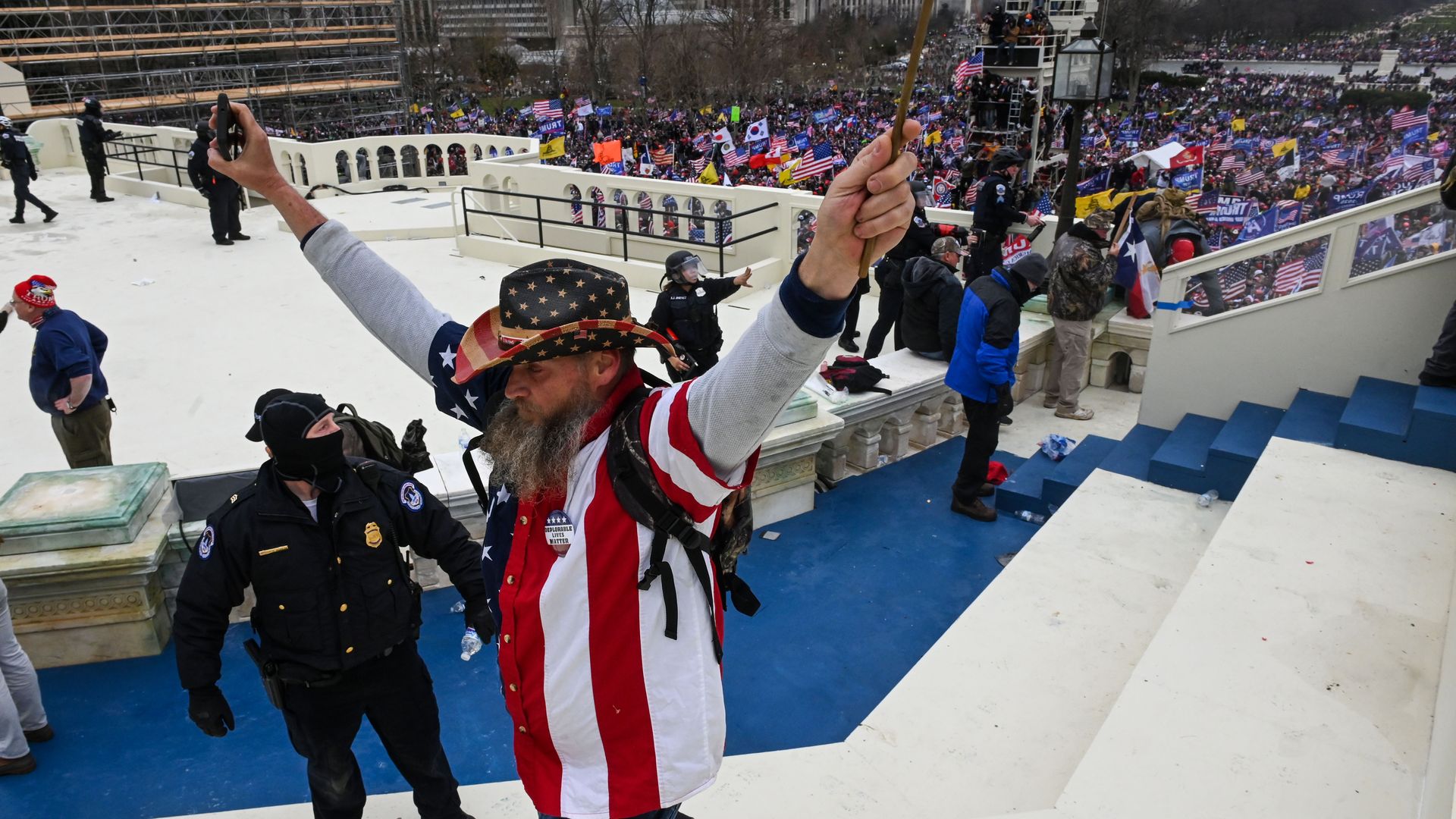 A rioter is seen flashing peace signs as he stands atop the inaugural platform during Wednesday's breach at the U.S. Capitol.