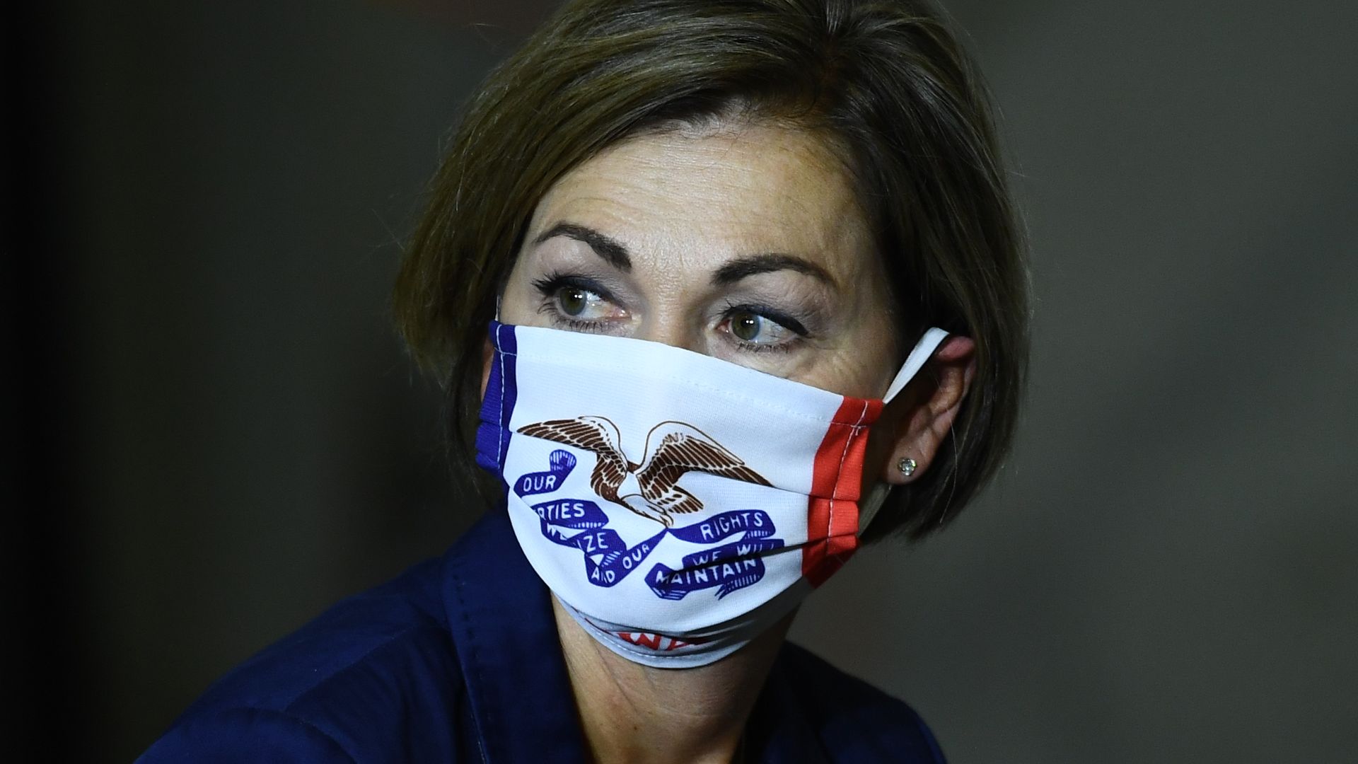 Iowa Gov. Kim Reynolds wears a mask while listening during a briefing.