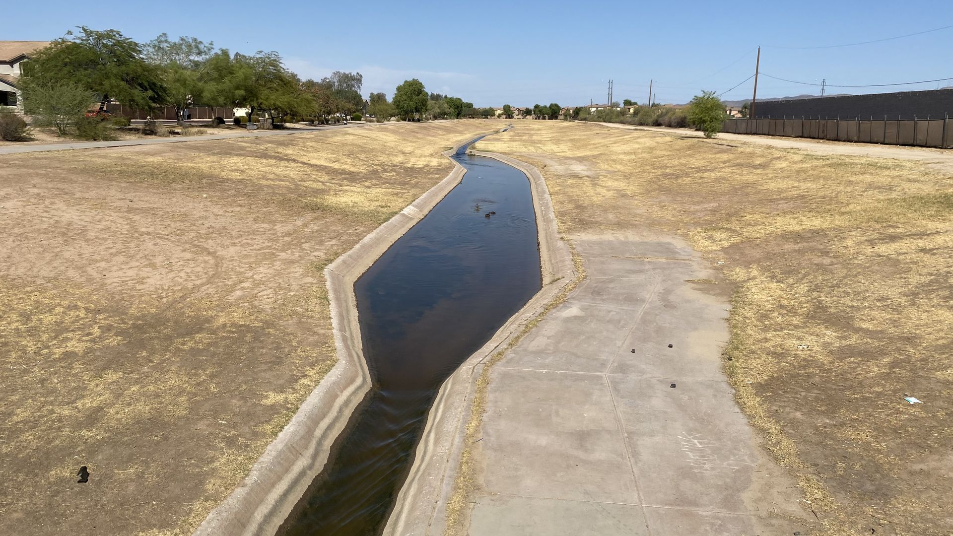 A small canal running through a patch of dry grass. 