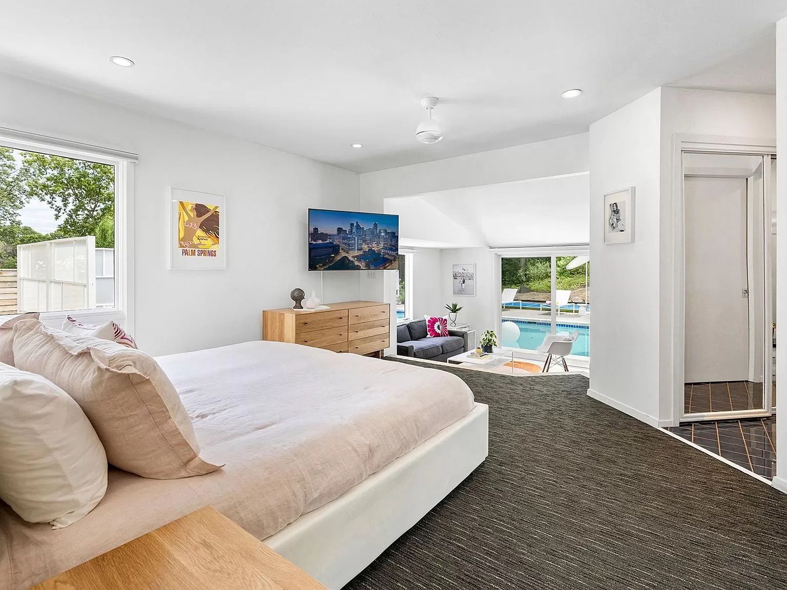 A bedroom with white walls, a pink bed and a television.