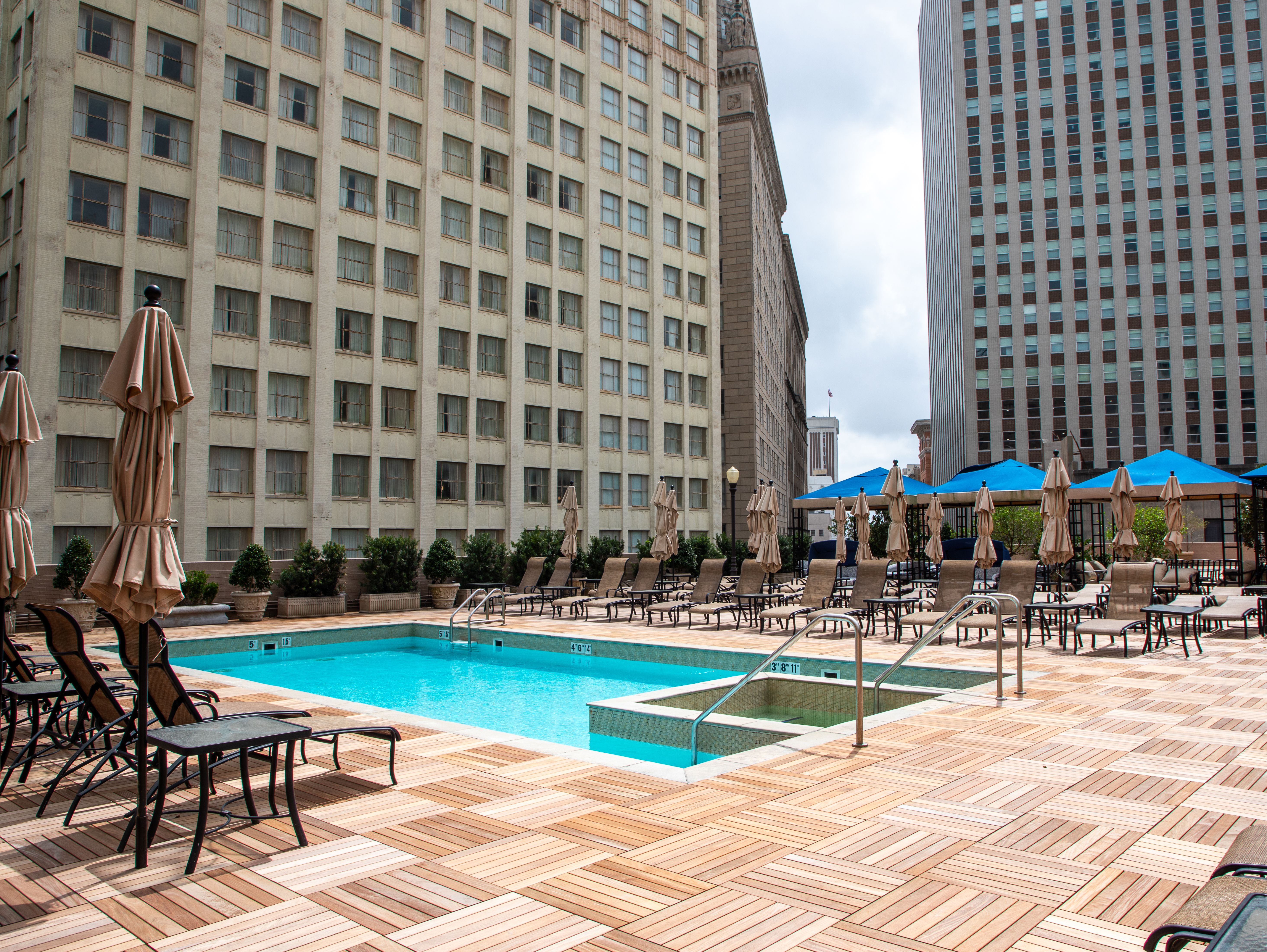 An empty rooftop pool deck with lounging chairs and umbrellas.