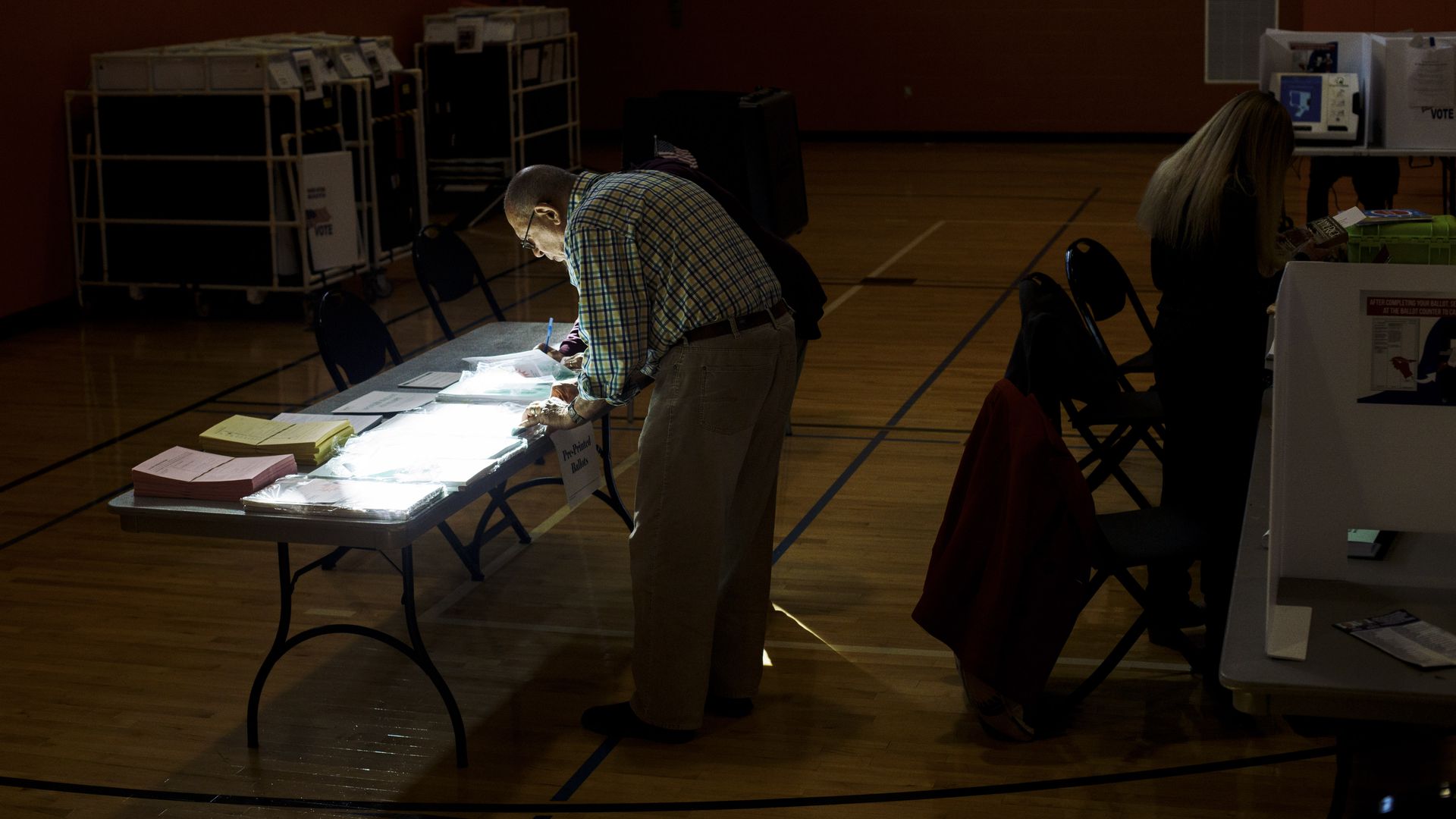 A poll worker helps a voter with their ballot.