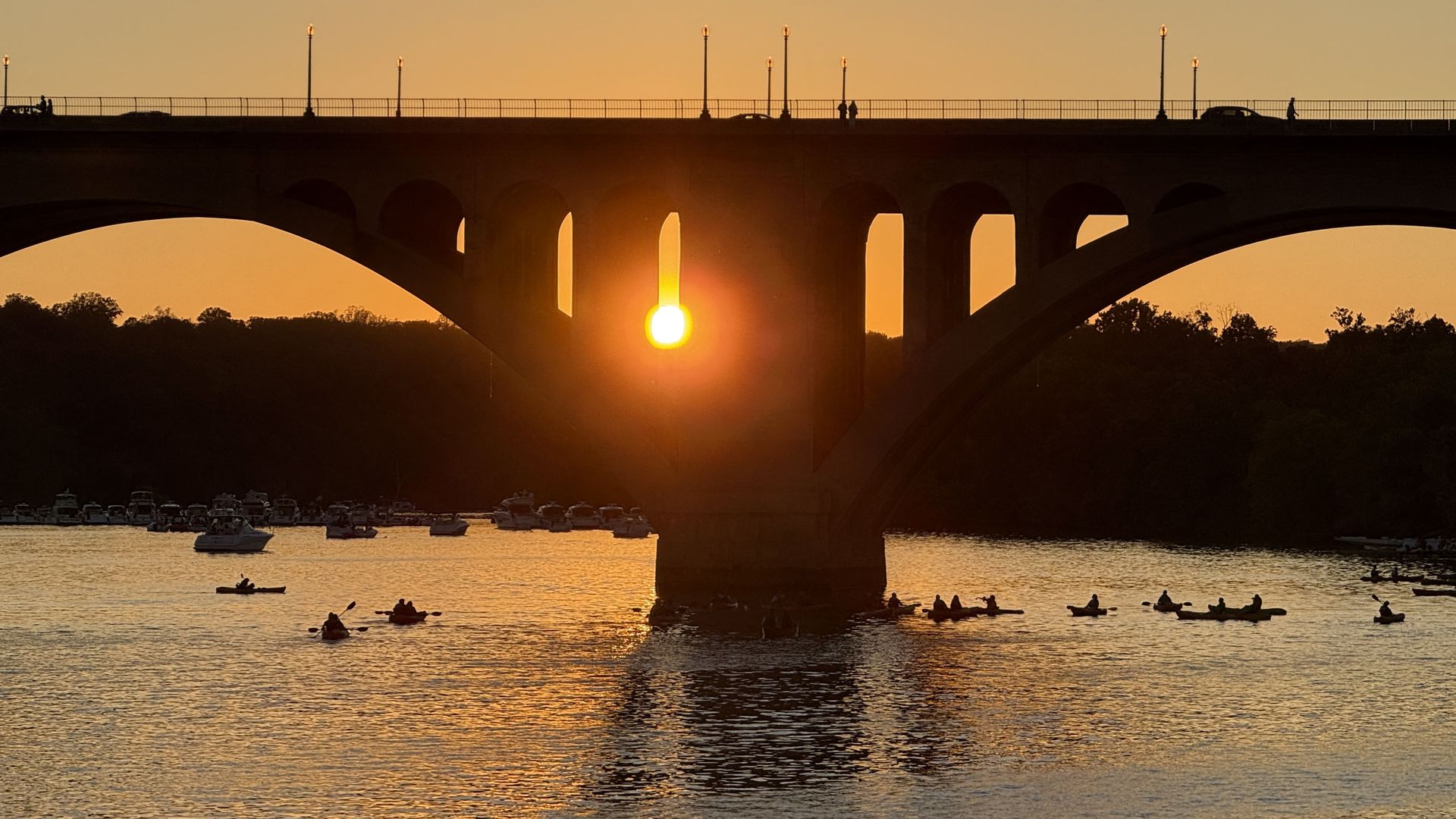 The Potomac River and Key Bridge at sunset with kayakers paddling 