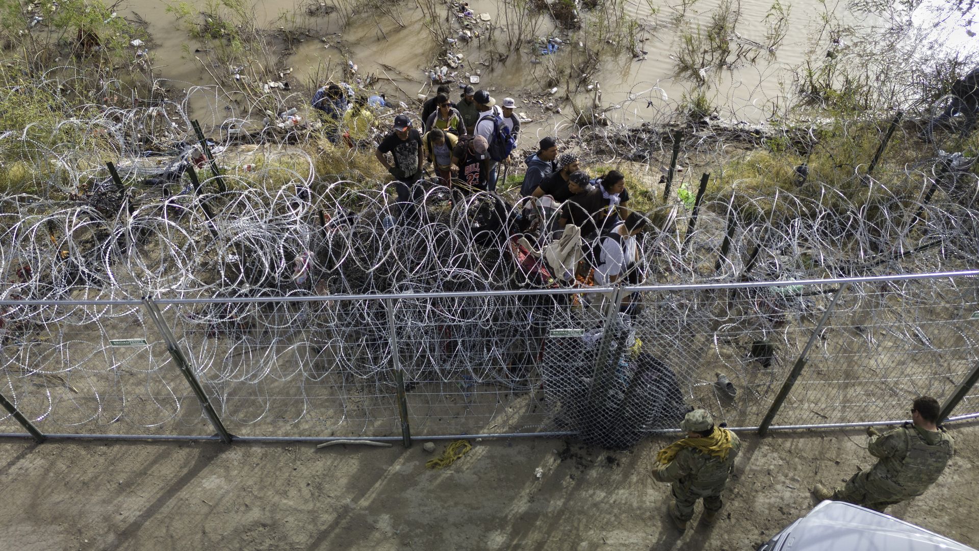 Texas National Guard soldiers prevent immigrants from passing through razor wire at the U.S.-Mexico border