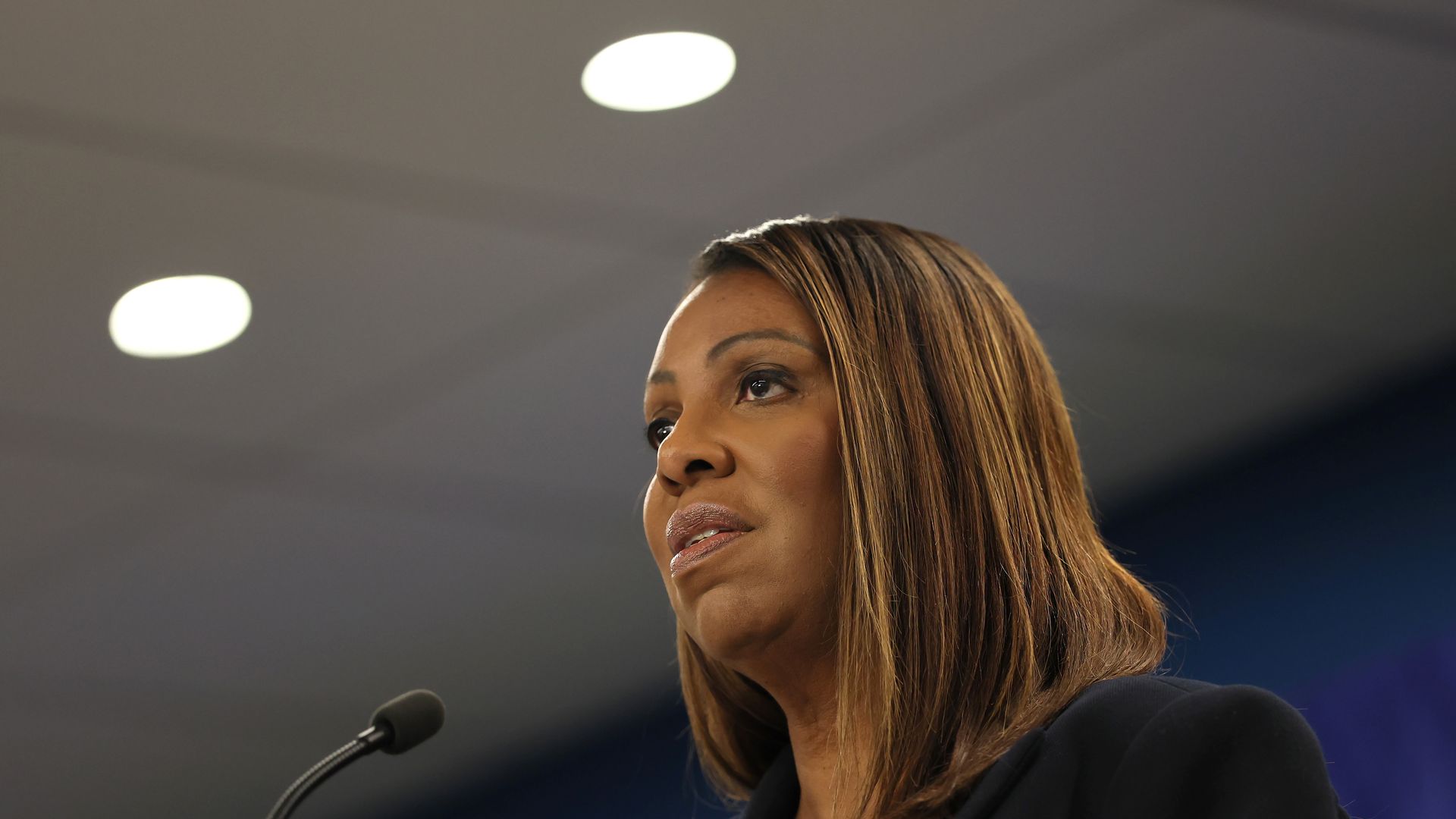 James, wearing a black suit speaking into a mic