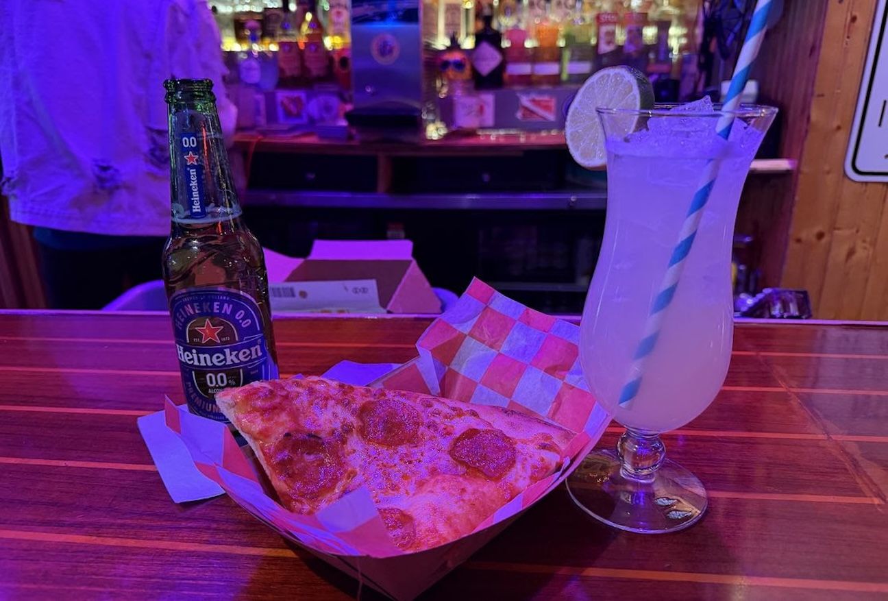Beer pizza and a cocktail in a dim bar. 