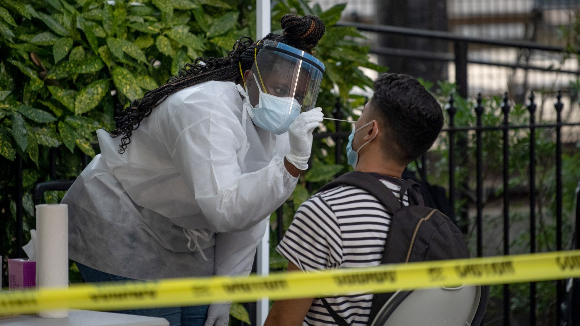 A medical worker wearing PPE administers a nasal swab test at a free coronavirus testing location 