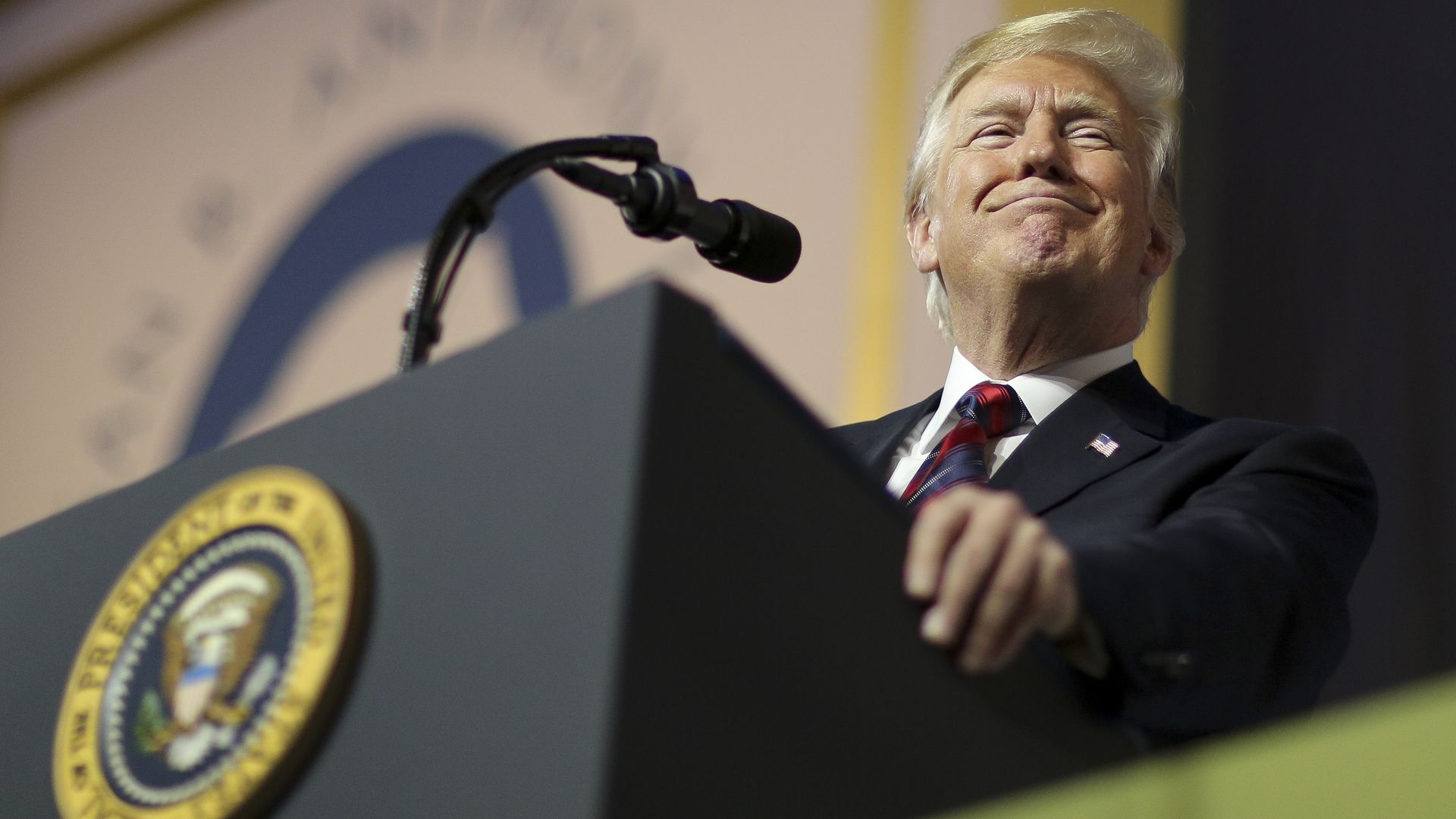 President Trump smiling at the podium.