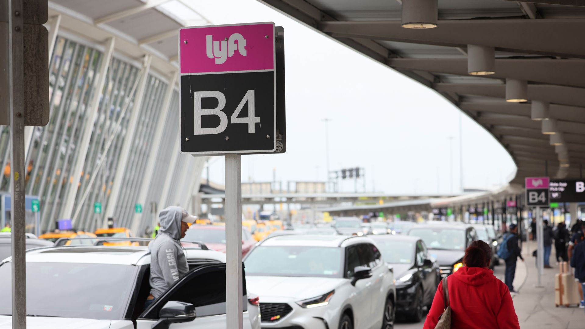 A Lyft sign at an airport arrivals curb