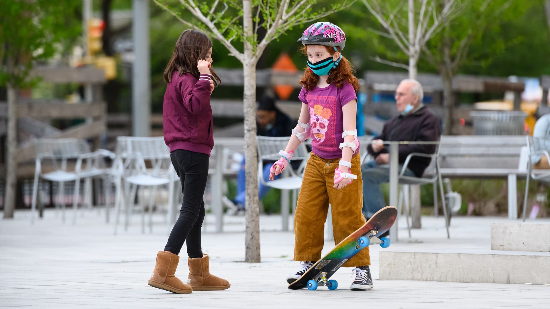 In this image, two girls meet while one skateboards