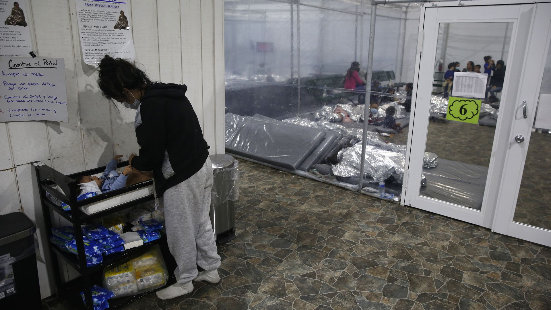 Photo of a person looking down at a baby in a detention facility
