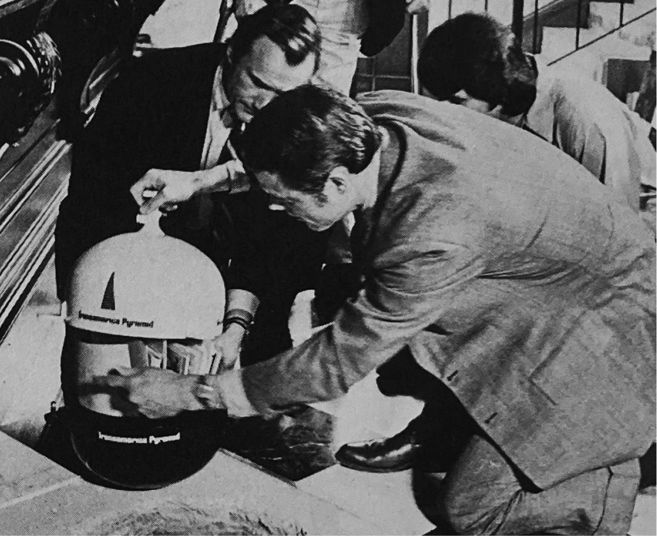 Black and white photo showing people going through the contents of a large, cylindrical time capsule
