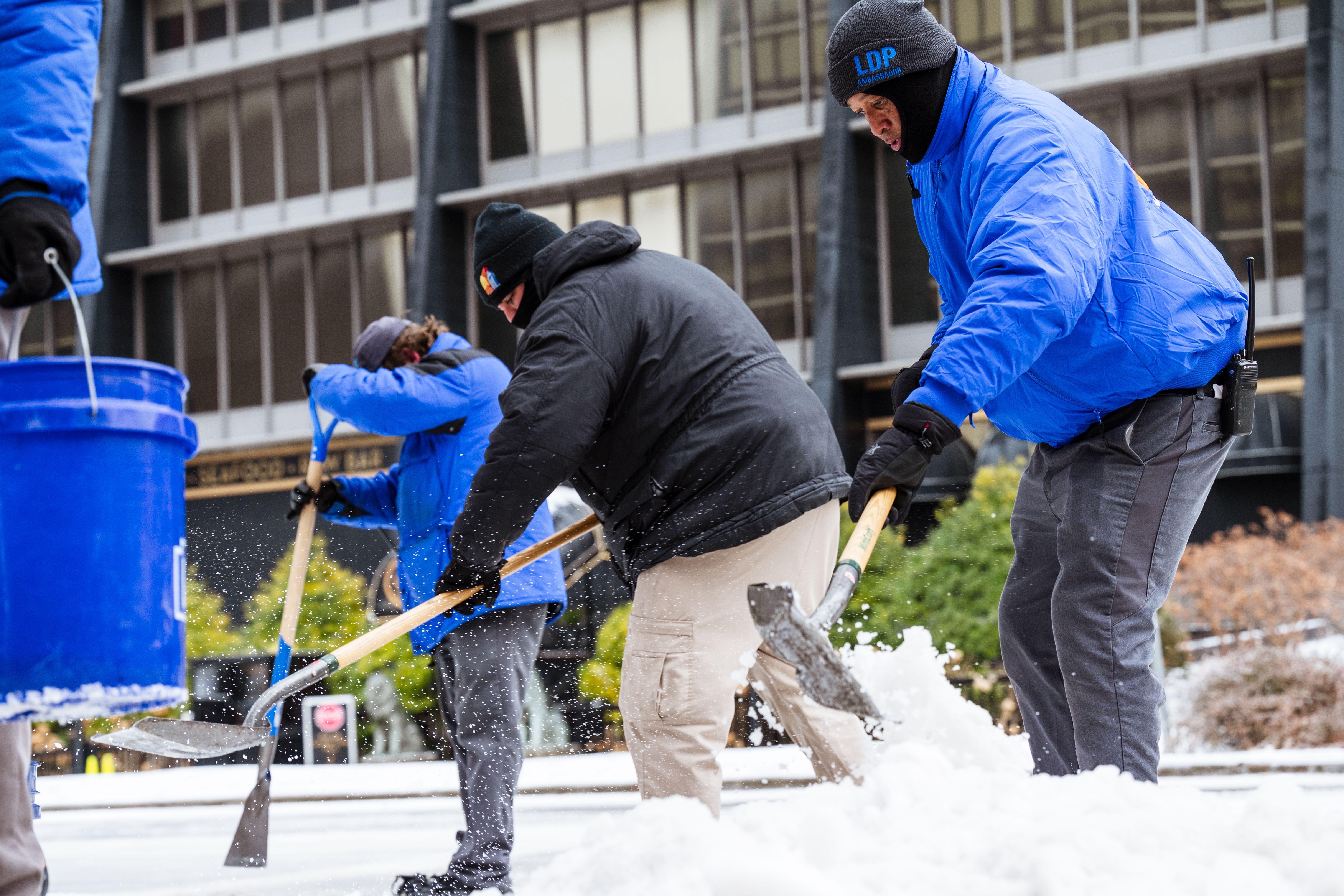 City workers use snow shovels to clear ice off of the sidewalk on February 11, 2021 in Louisville, Kentucky. 