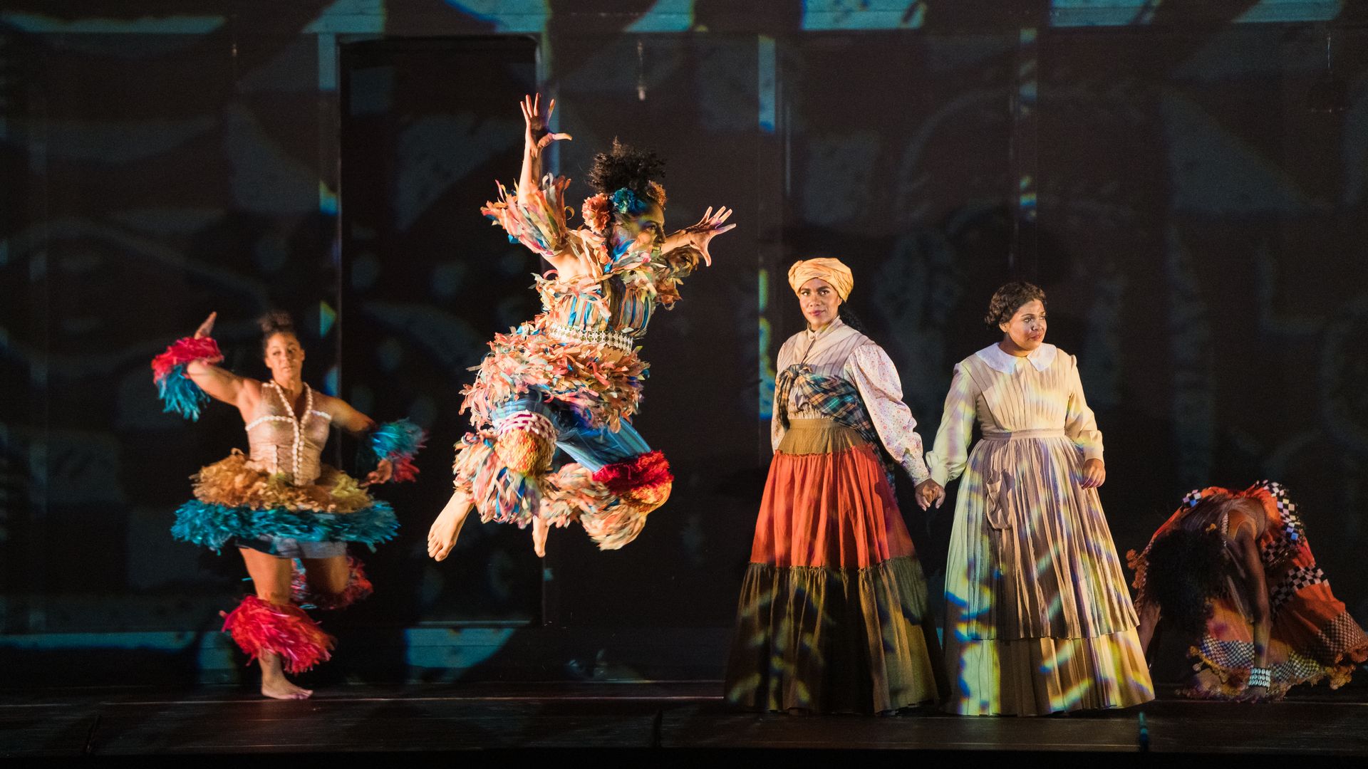 Photo of people on stage, with dancers in African attire dancing in a contemporary way. 
