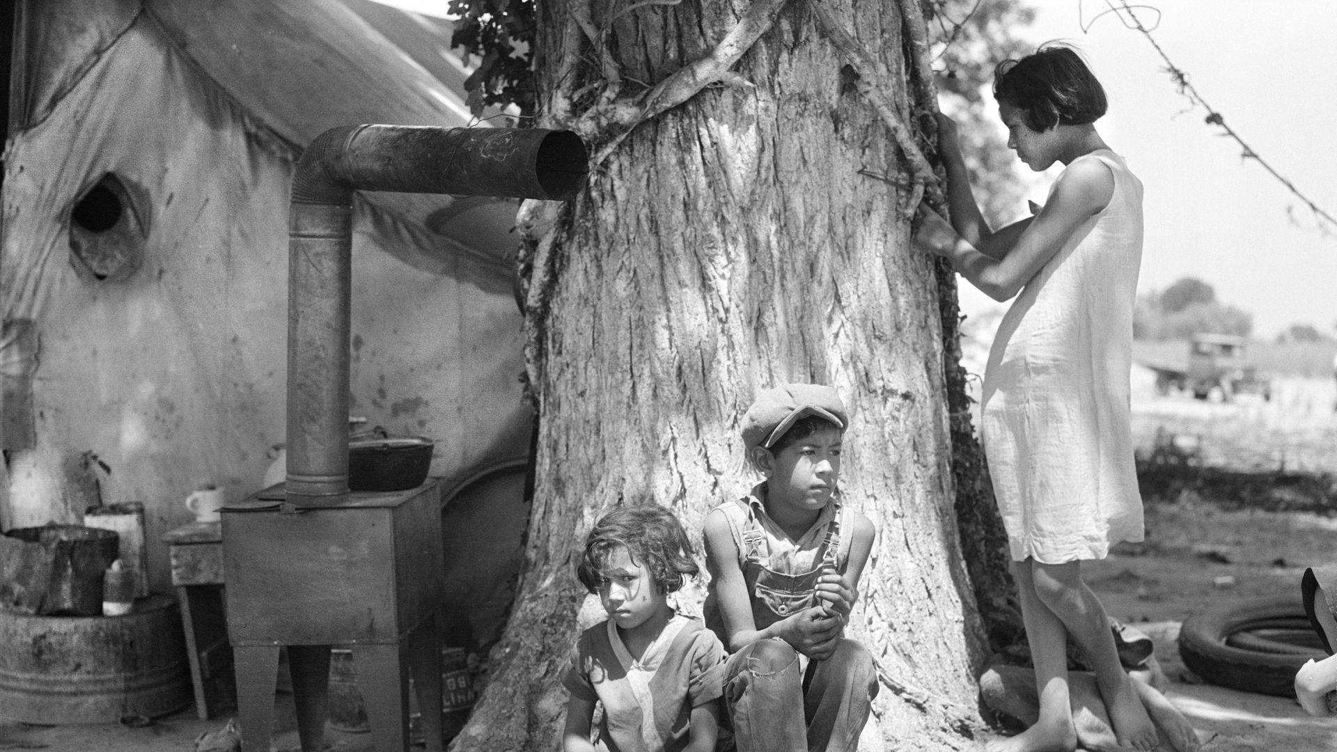 Unaccompanied migrant Mexican American children sit by a tree in 1935.