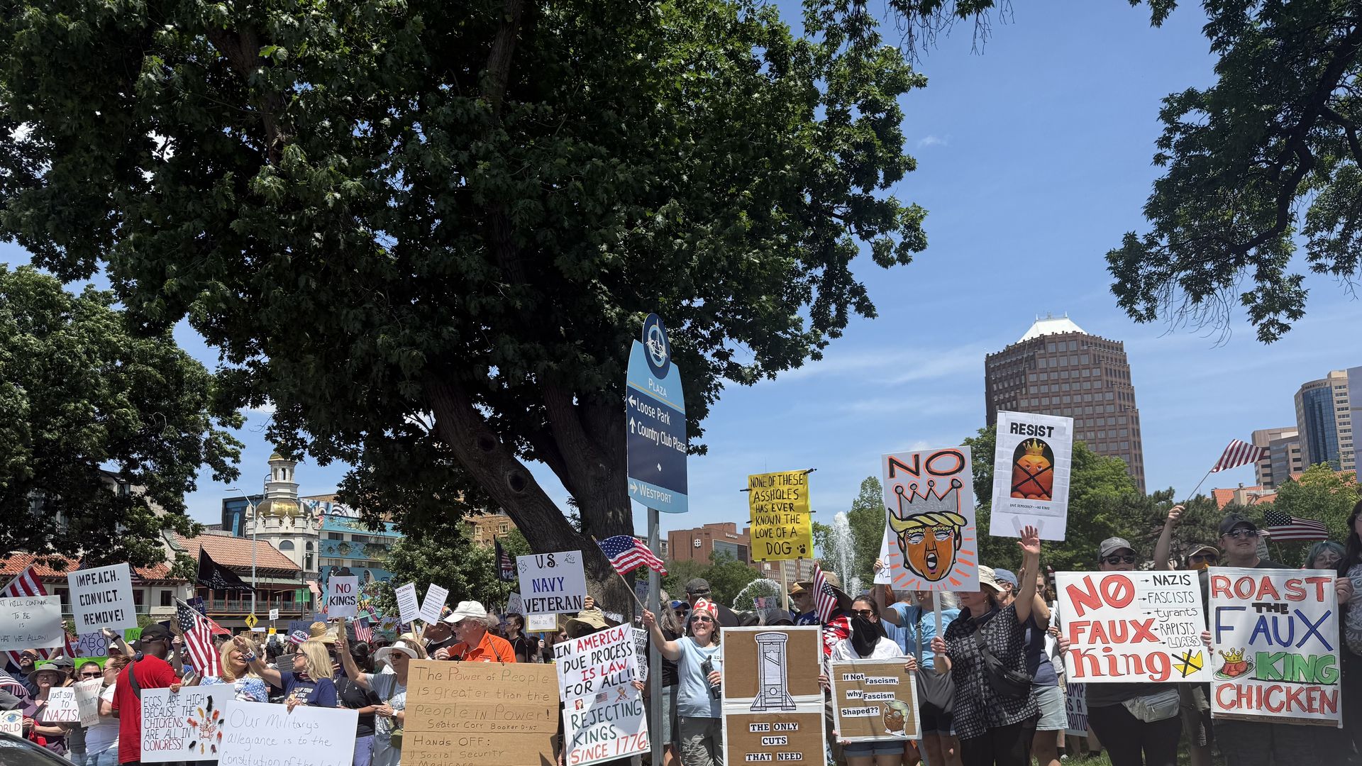 Photo shows protesters at a "No Kings" rally near the Plaza in Kansas City holding signs out toward traffic.