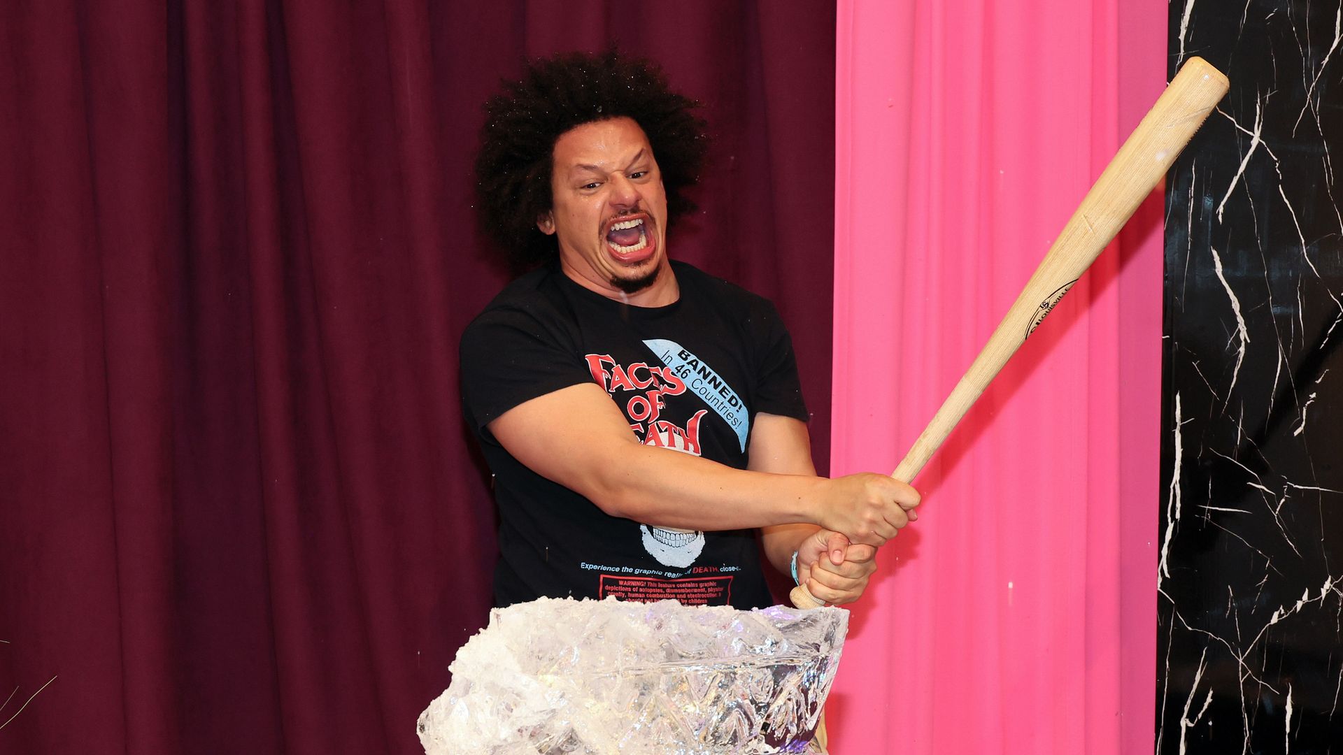 A photo of a man with an angry look on his face wielding a bat and preparing to hit an ice sculpture