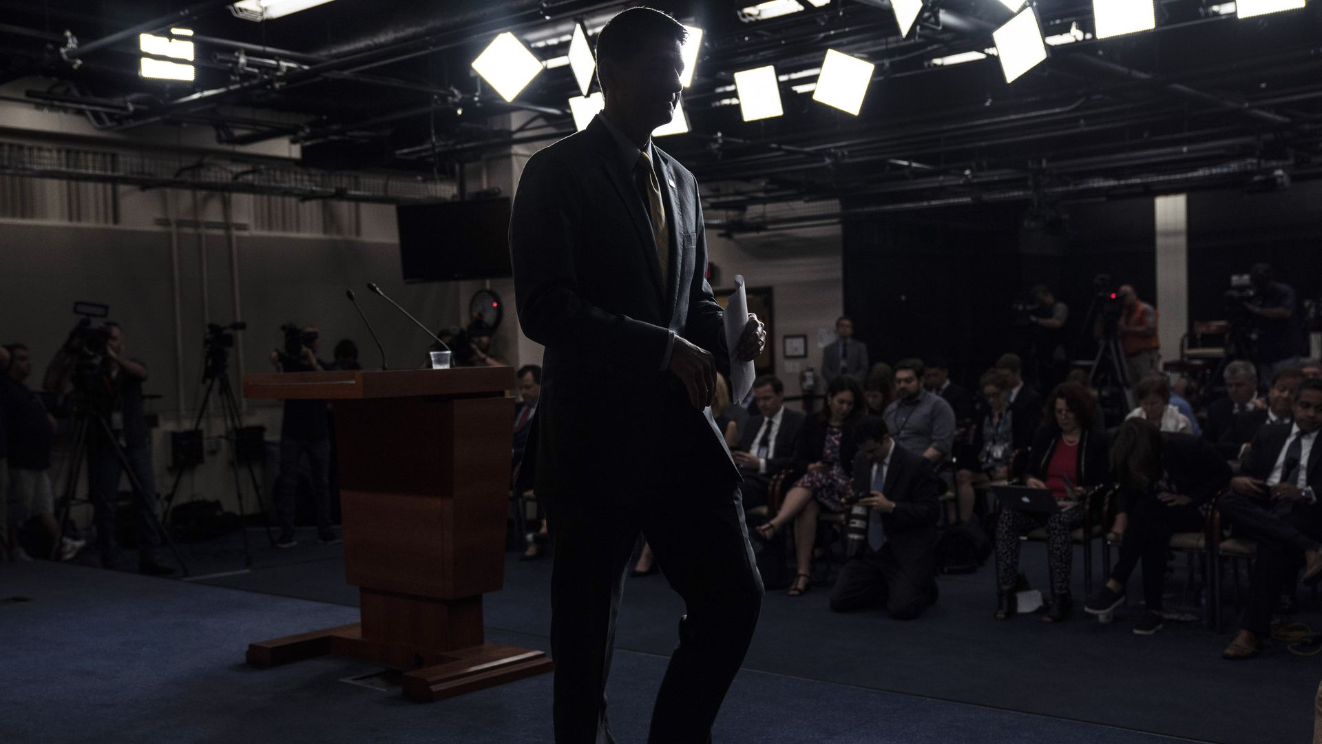 The darkened outline of Paul Ryan walking away from the podium where he spoke to reporters 
