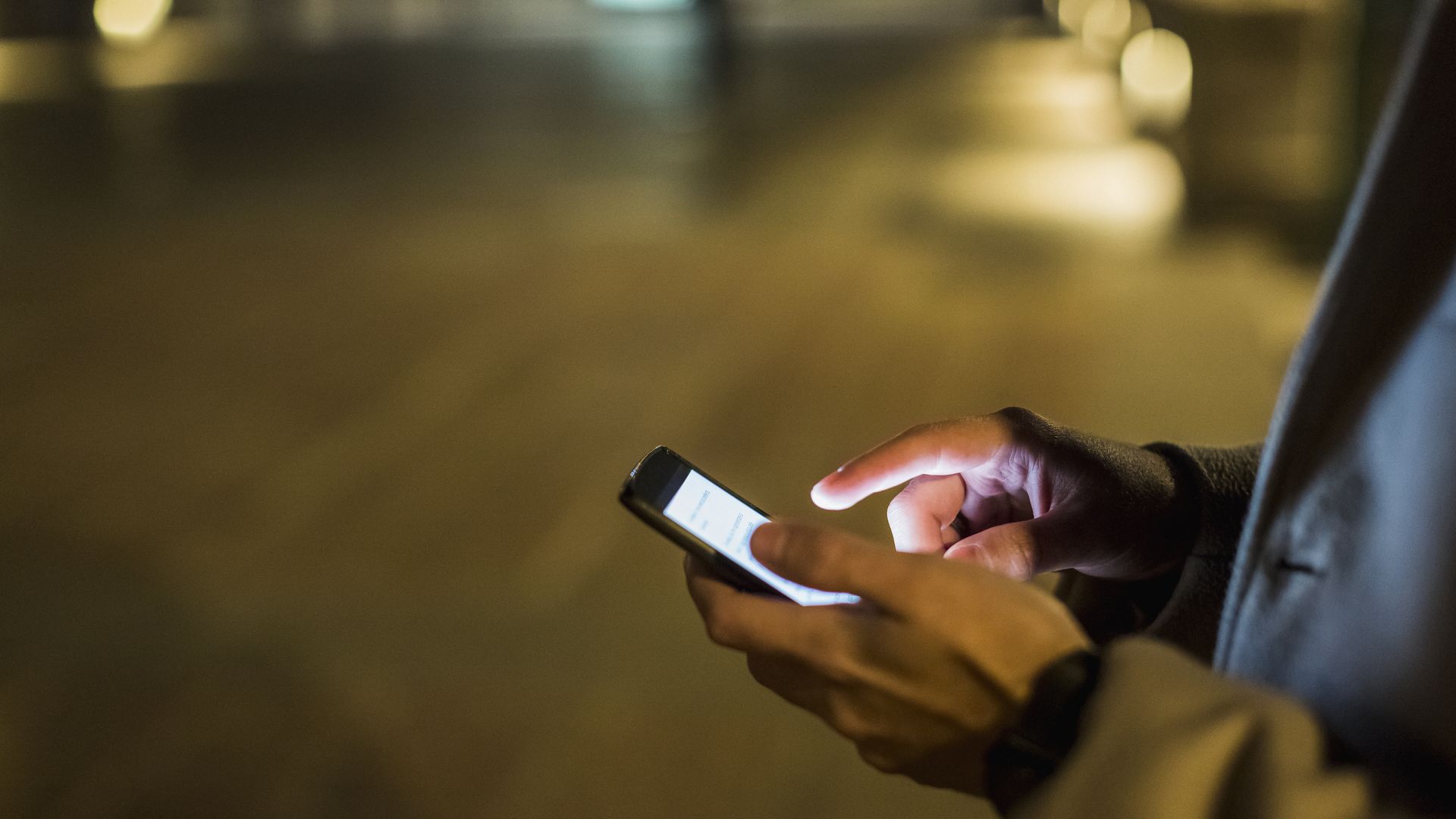 Photo of a man outdoors at night using a cellphone.