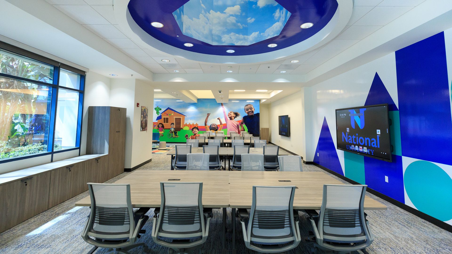A room in a university building with a skydome, conference tables and chairs and a kids play area. 