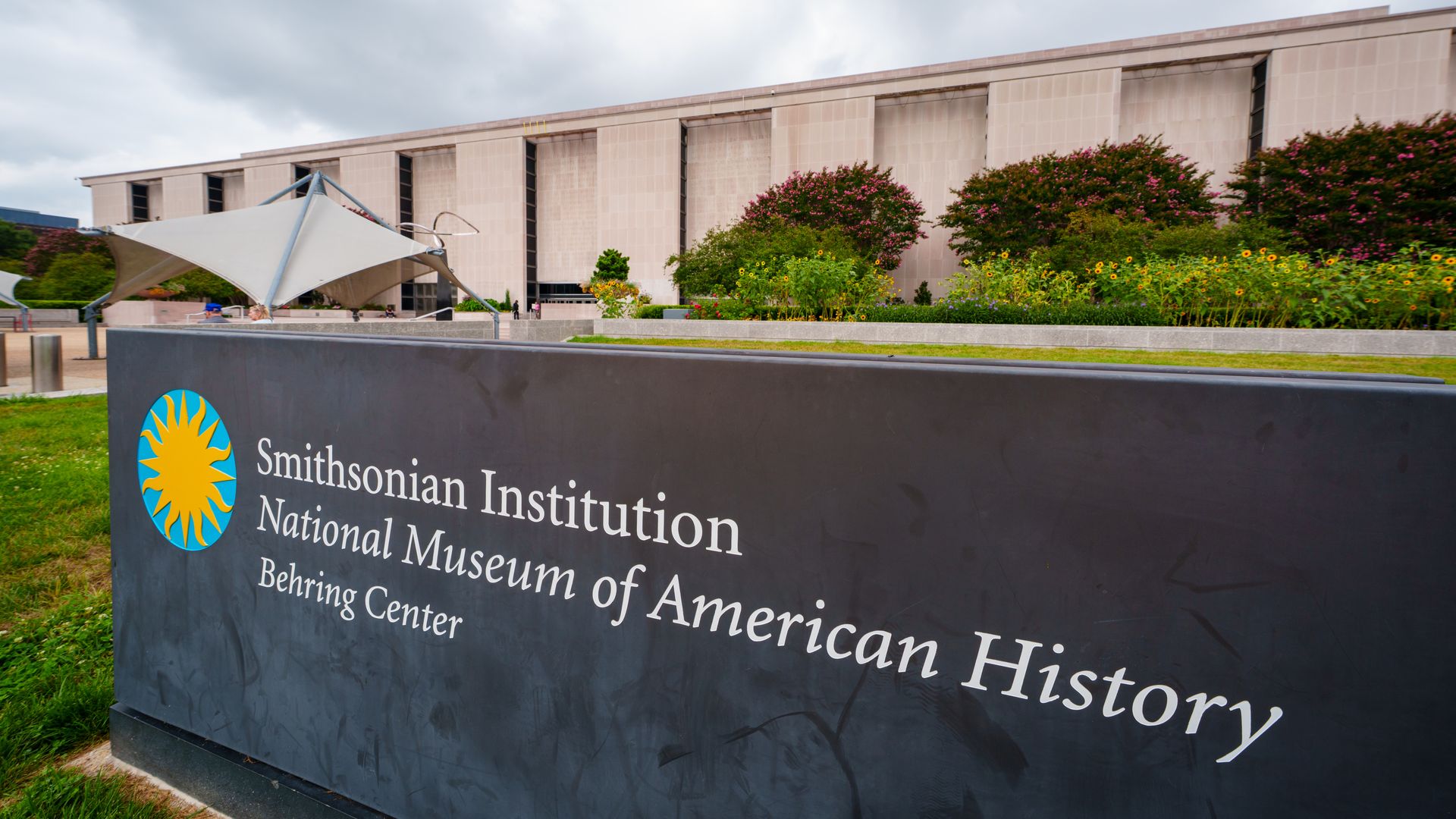 A sign outside a large concrete building marks it as National Museum of American History. 