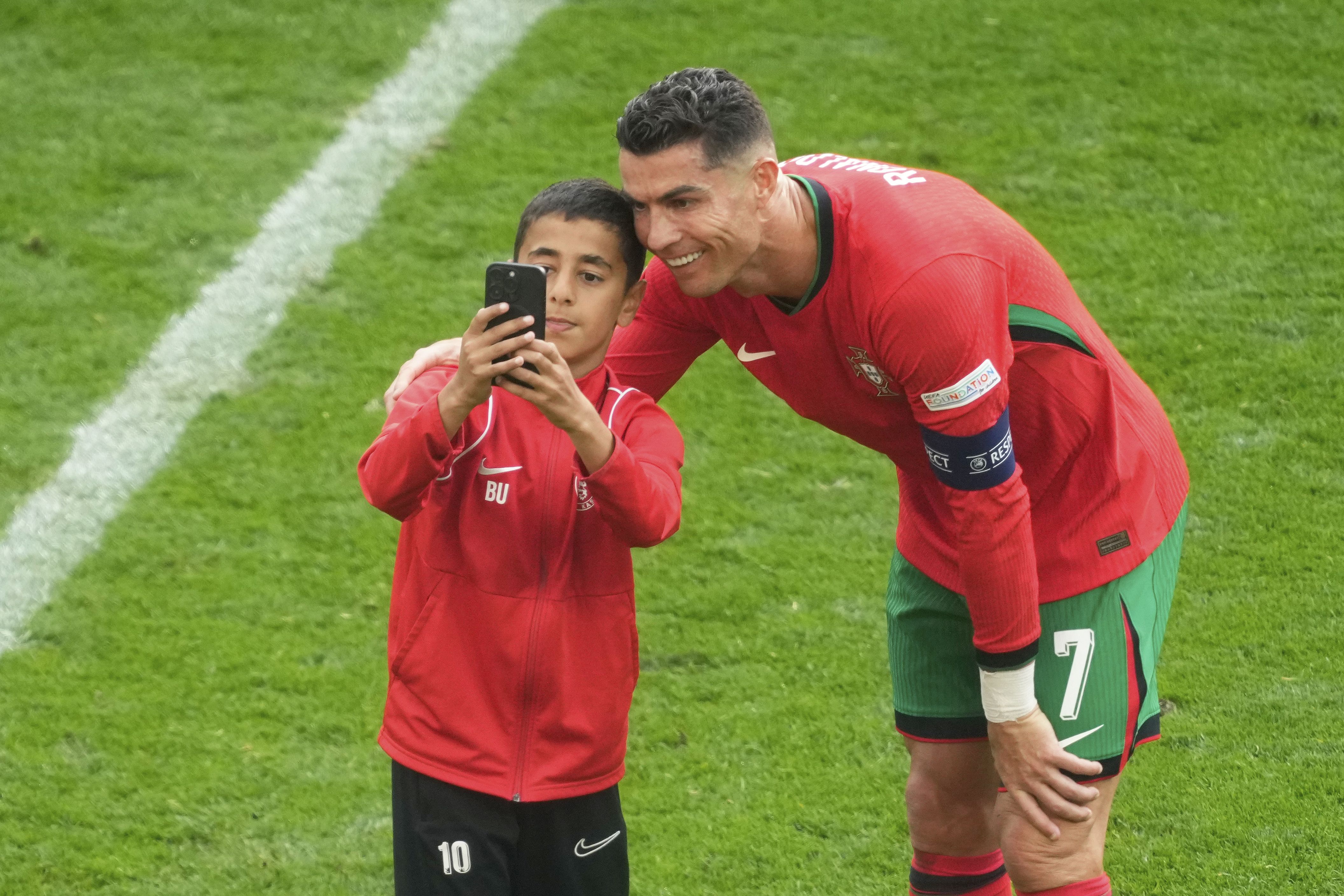 A young pitch invader takes a selfie with Portugal's Cristiano Ronaldo during a Group F match between Turkey and Portugal at the Euro 2024 soccer tournament in Dortmund, Germany, Saturday, June 22