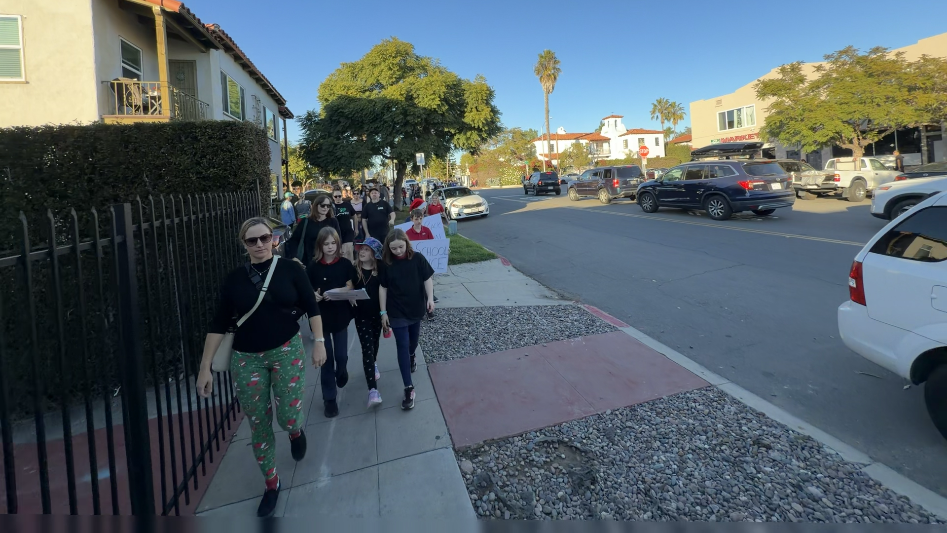 Parents and kids walk down the street in protest.