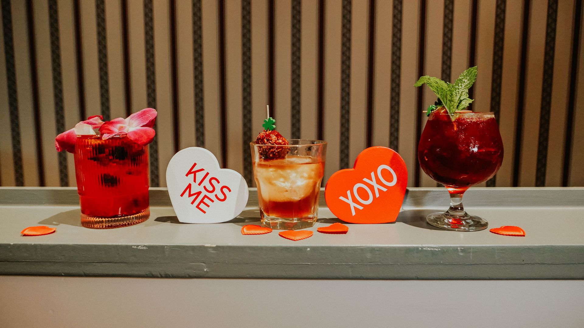 Three cocktails and two hearts with the phrases "kiss me" and "xoxo" on them. 