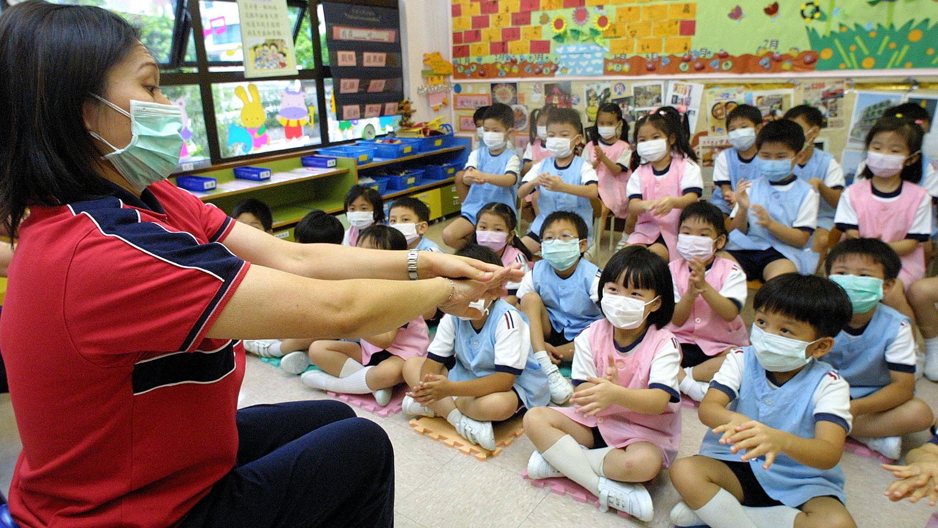 Image of a teacher in Hong Kong addressing a class of masked children on hand hygiene for COVID-19.