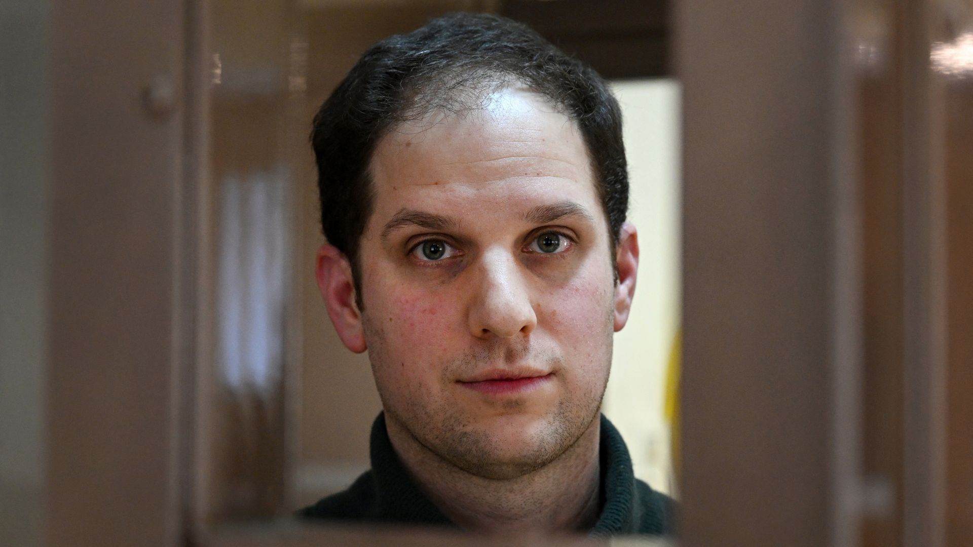 Evan Gershkovich looks out from inside a defendants' cage.