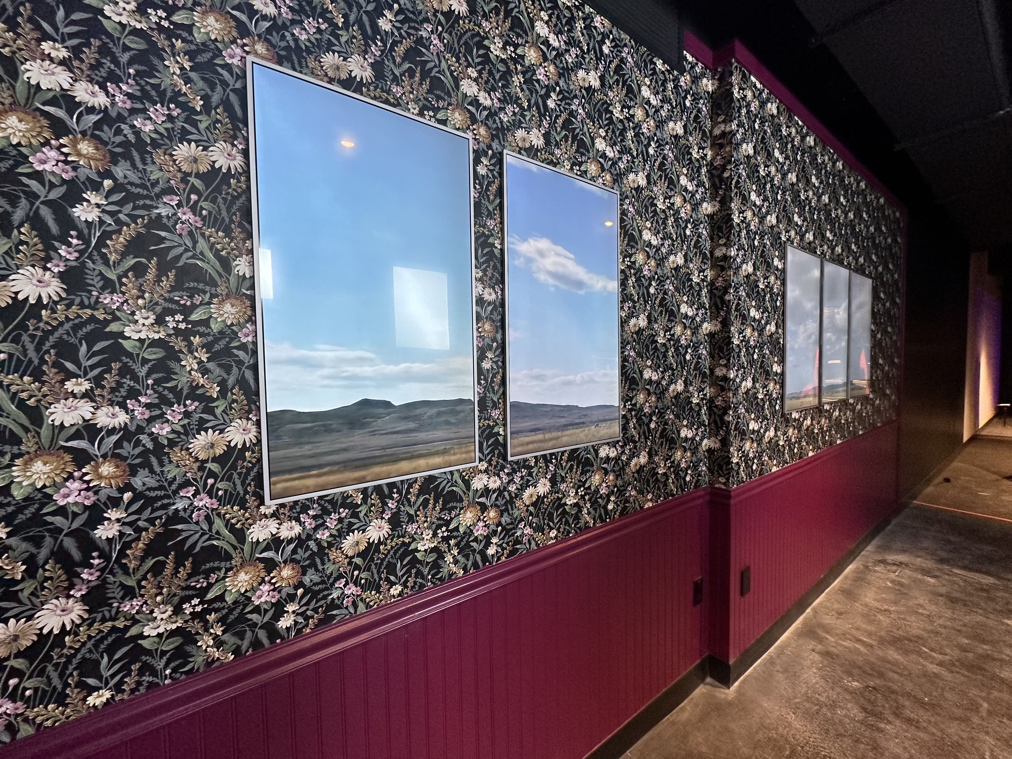 Computer panels appear as windows showing a field on a partly cloudy day in the "living gallery" of the WNDR Museum in Boston.