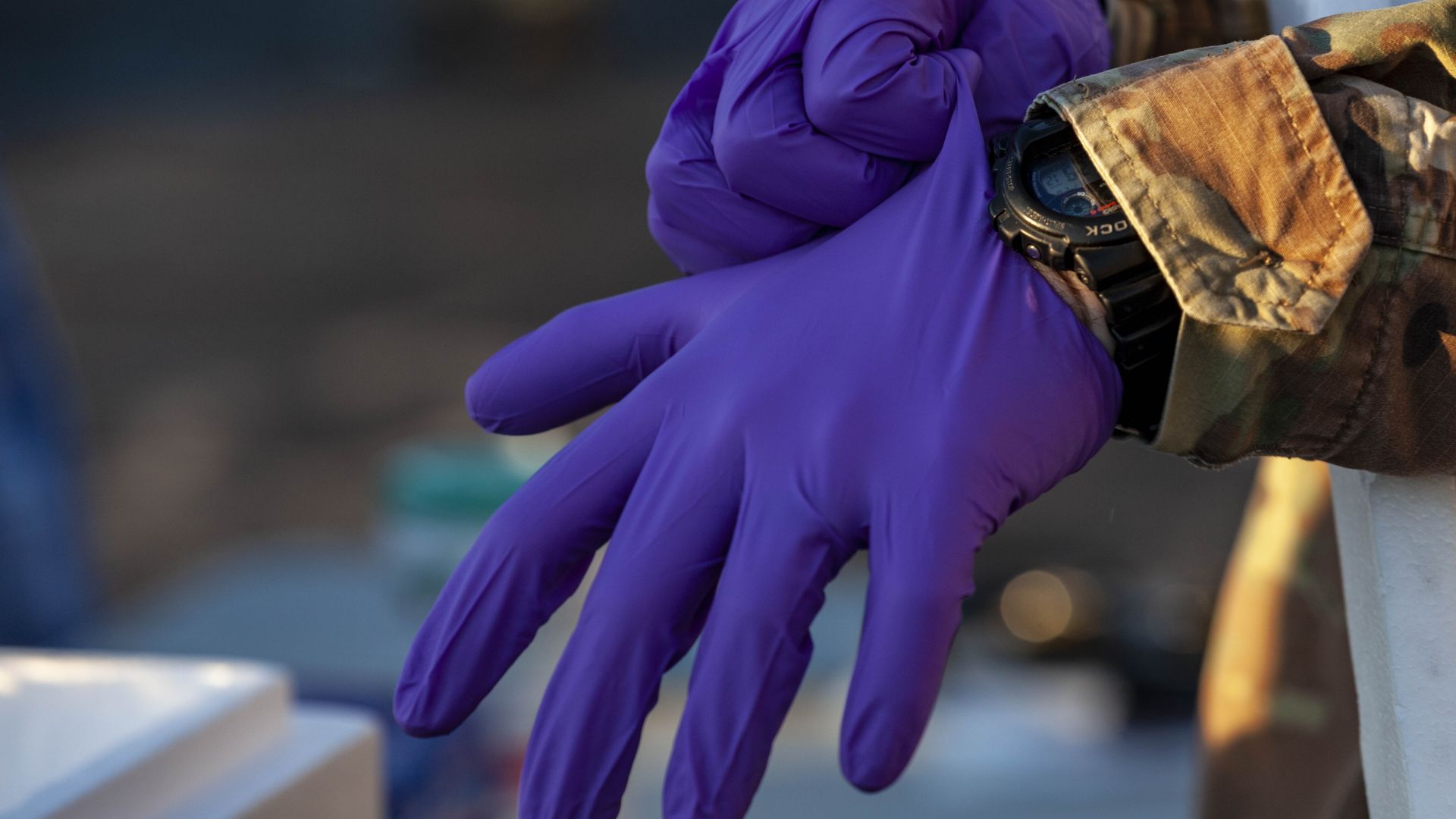 An Ohio National Guard member puts on a rubber glove while helping at a COVID testing site.