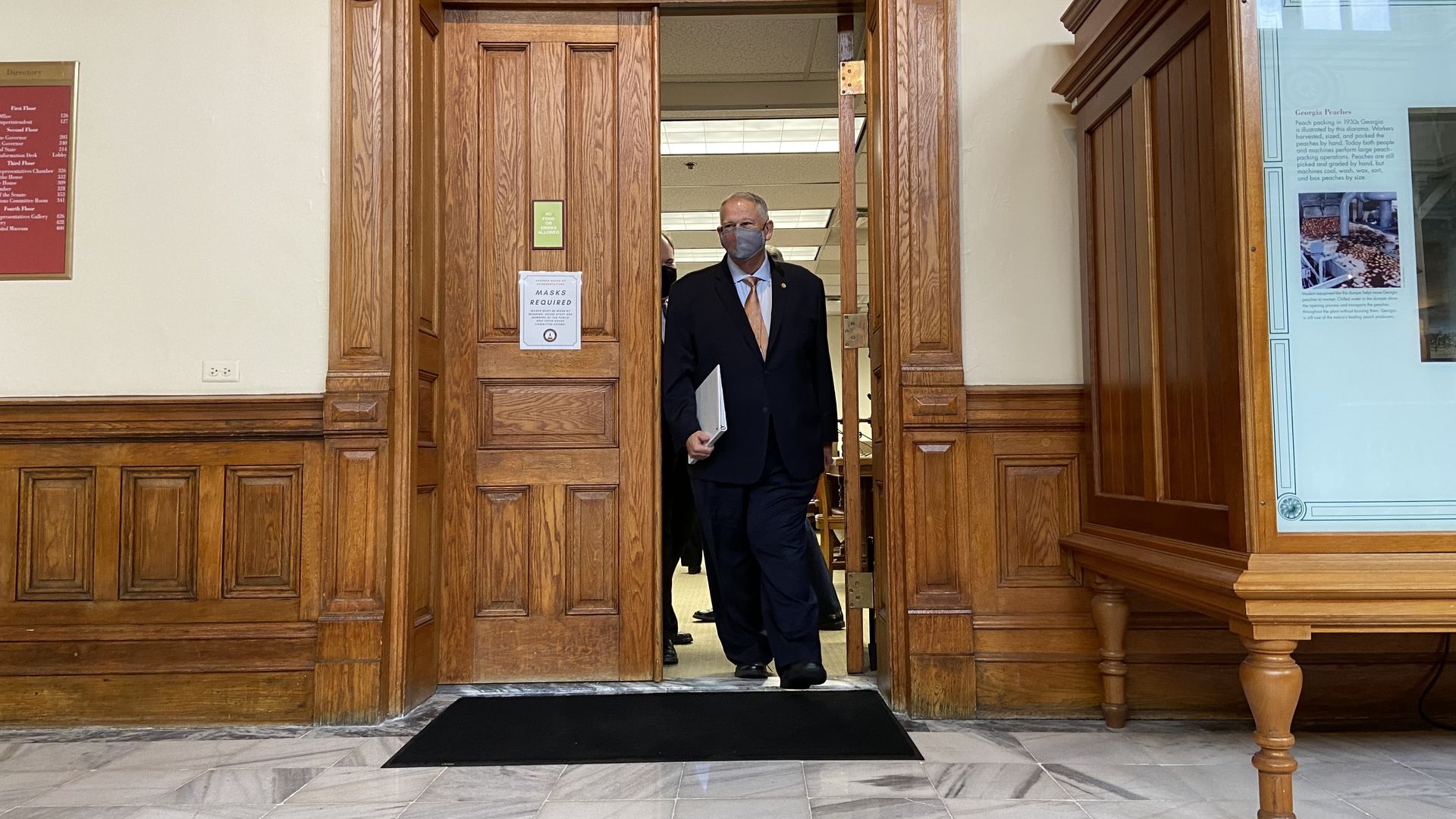 David Ralston, wearing a mask and a suit, walks out of a conference room in the Georgia Capitol